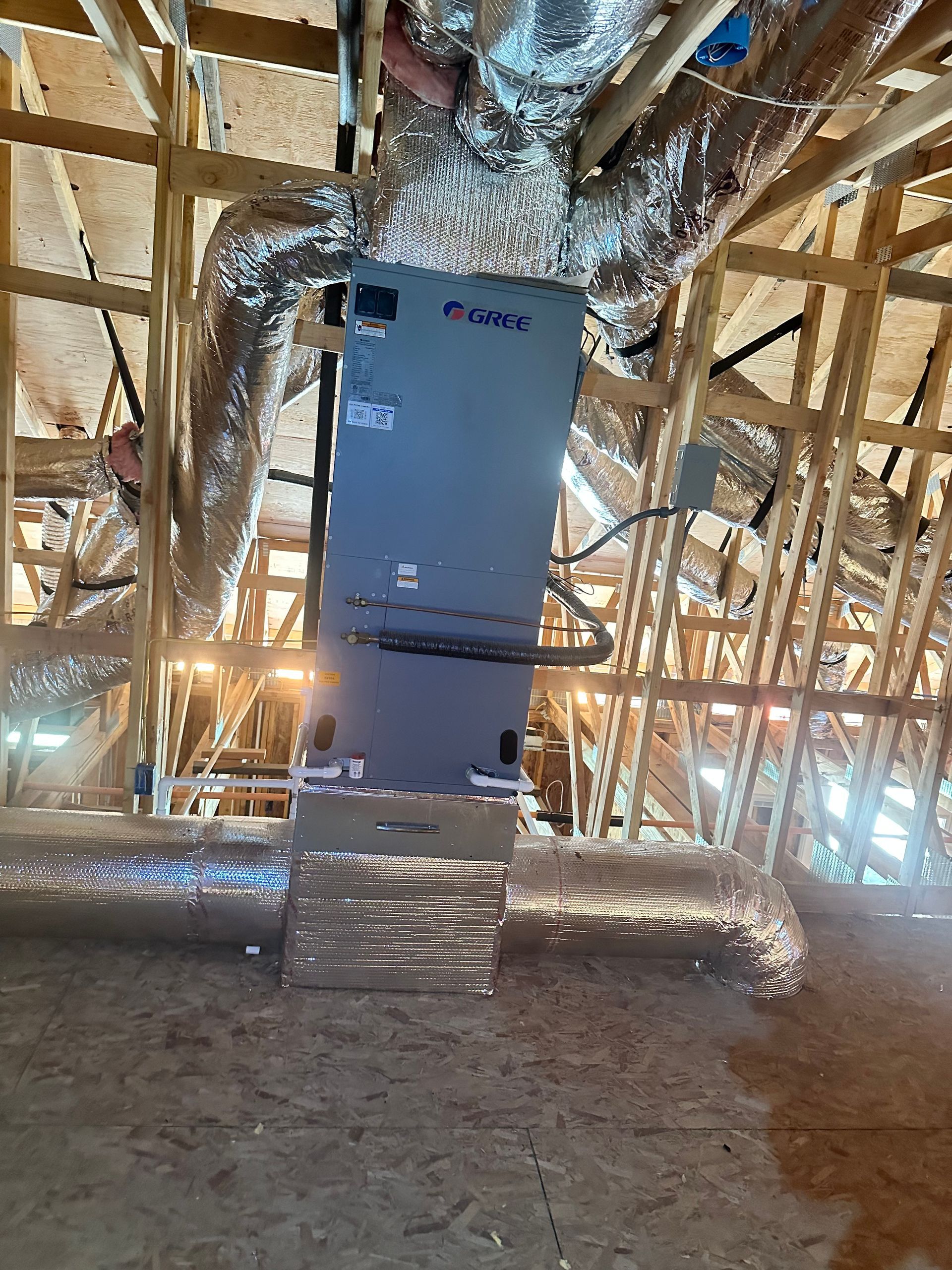 A large air conditioner is hanging from the ceiling of a building under construction.
