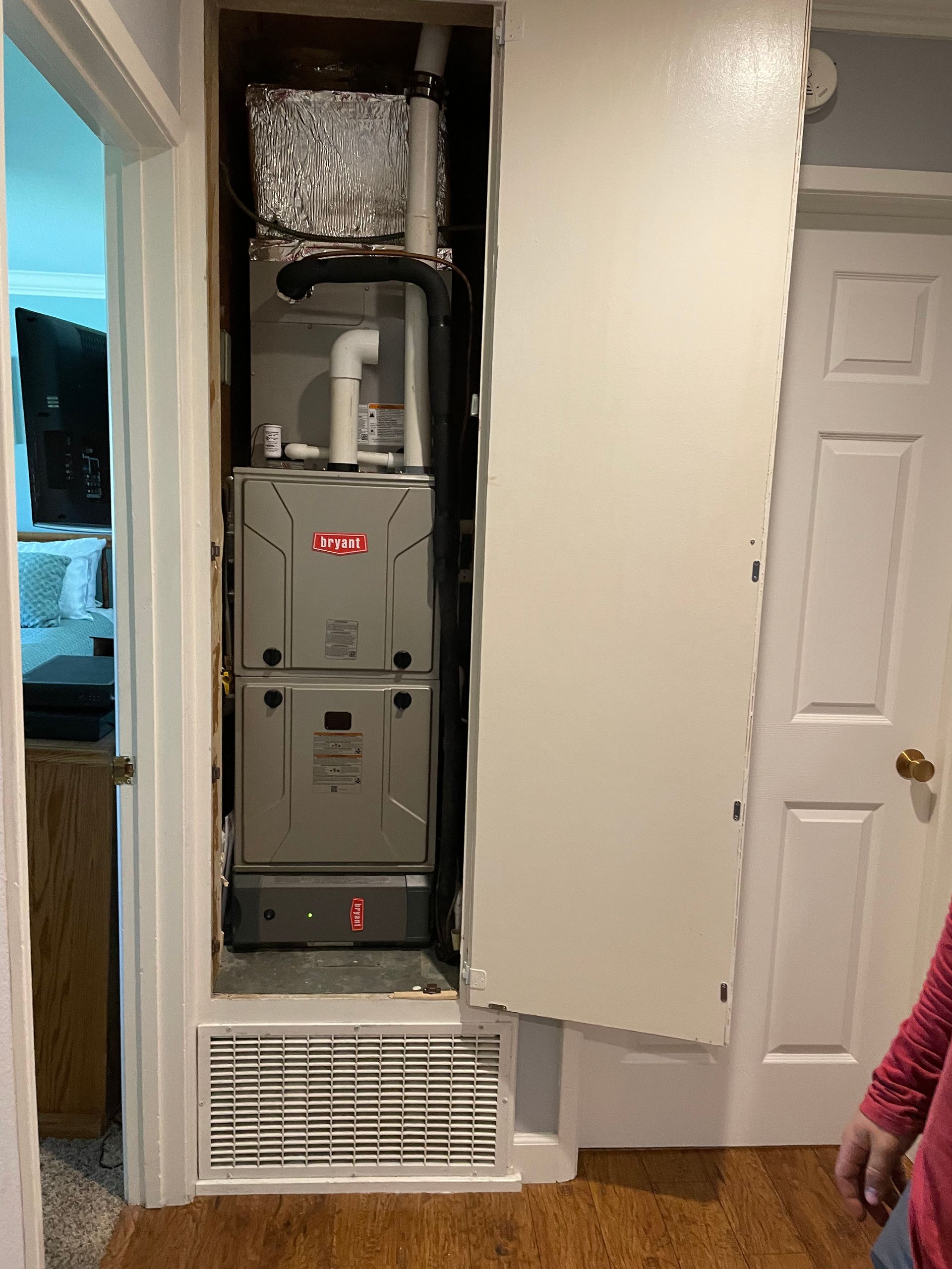 A person is standing in a hallway next to a furnace.