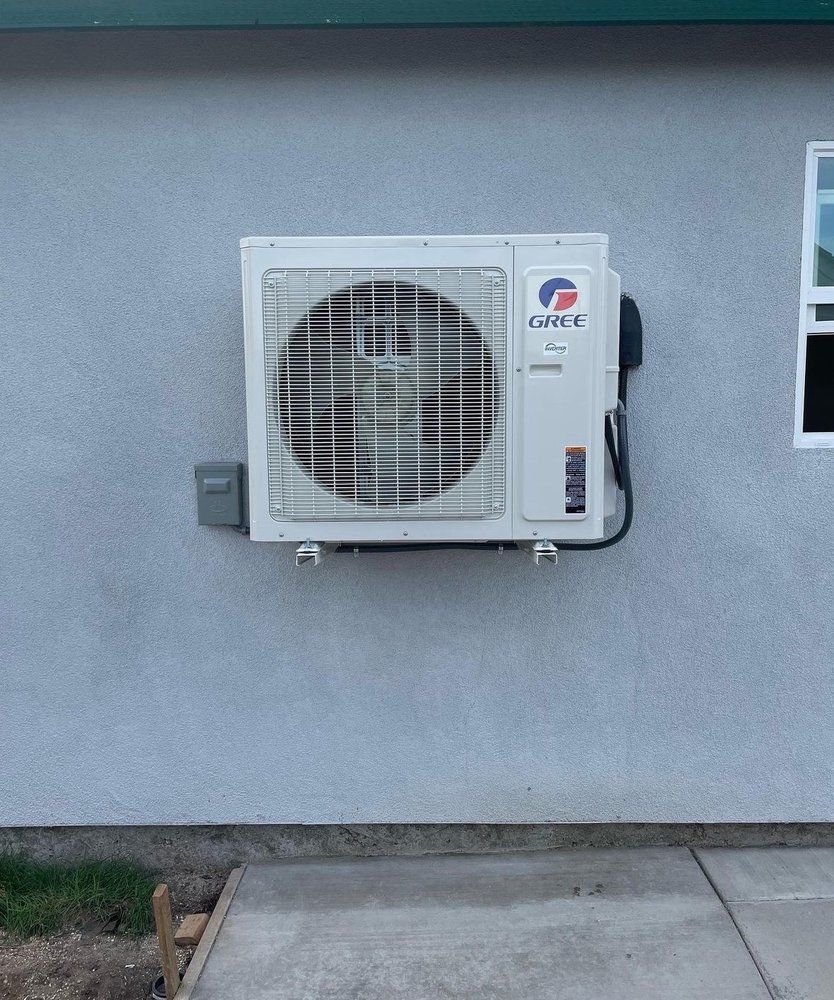 A white air conditioner is mounted on the side of a building | Heating & Airflow