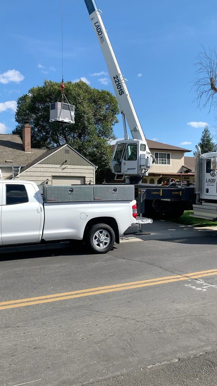 A white truck is parked on the side of the road next to a crane | Heating & Airflow