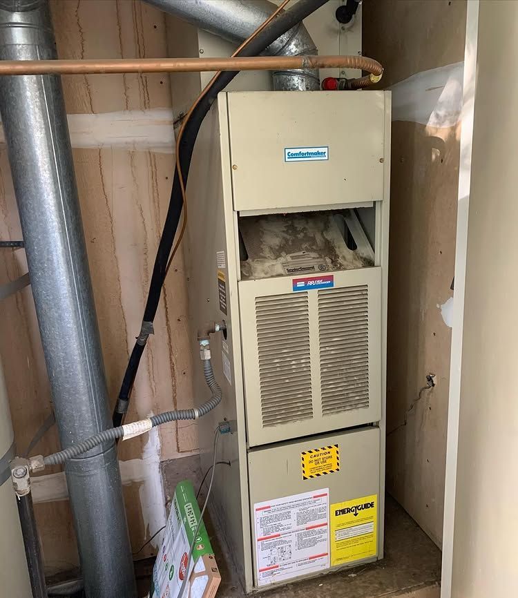 A furnace is sitting in a room next to a pipe | Heating & Airflow