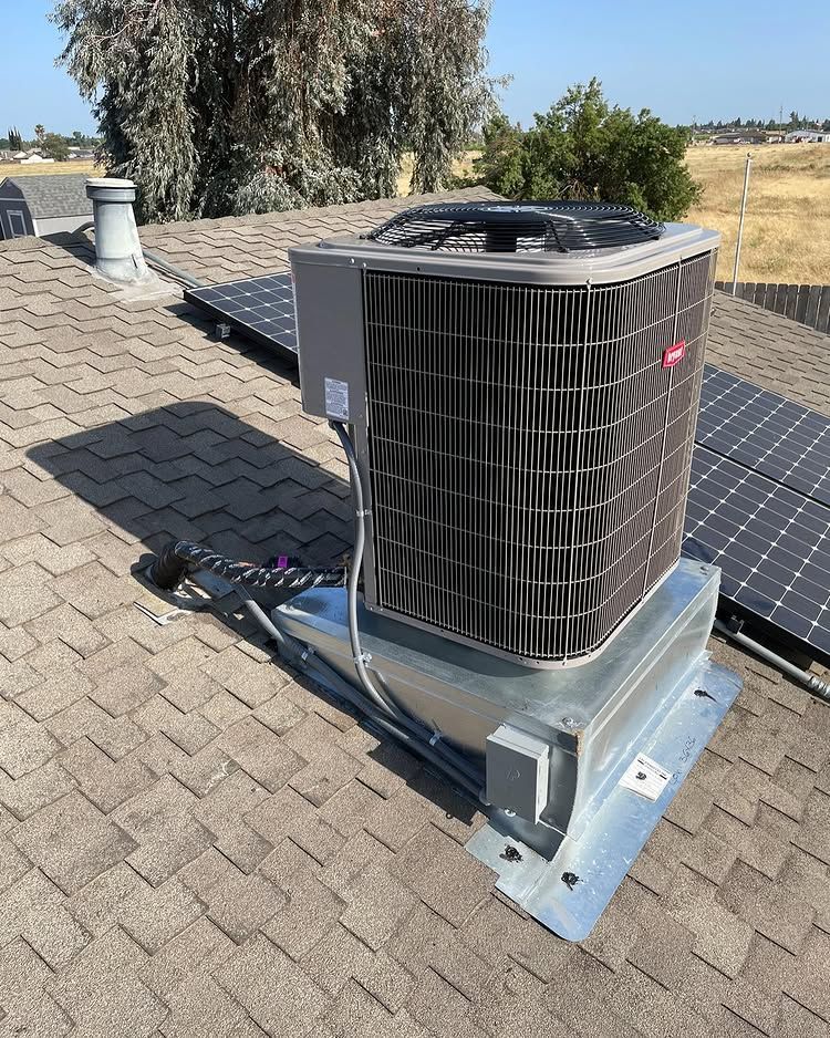 An air conditioner is sitting on top of a roof next to a solar panel | Heating & Airflow