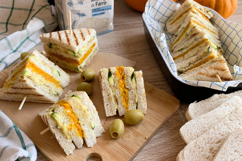 Un tagliere di legno con tramezzini e olive