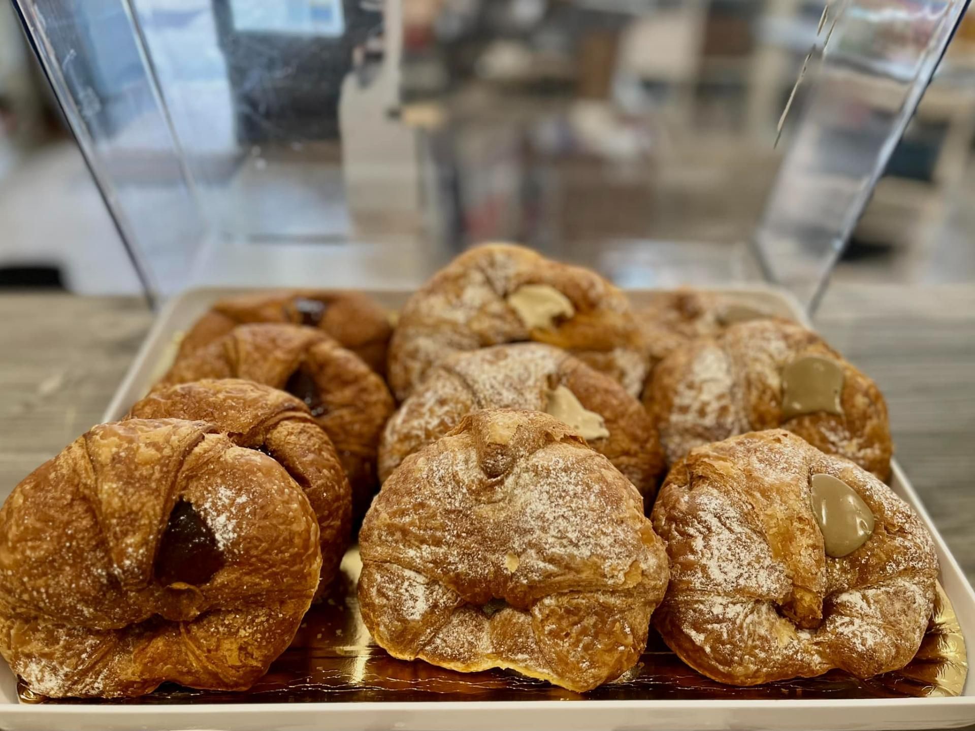 Su un tavolo un vassoio di croissant ricoperti di zucchero a velo.