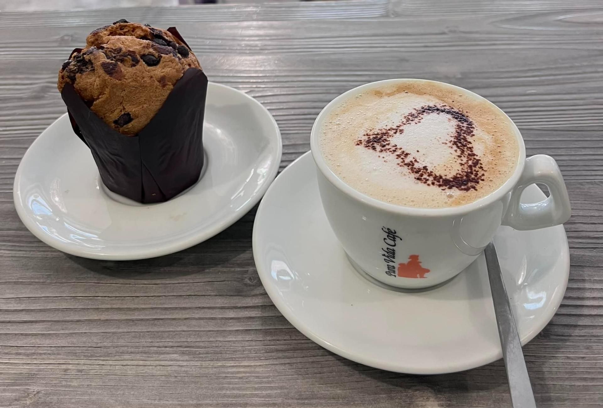 Una tazza di caffè e un muffin su un piattino su un tavolo