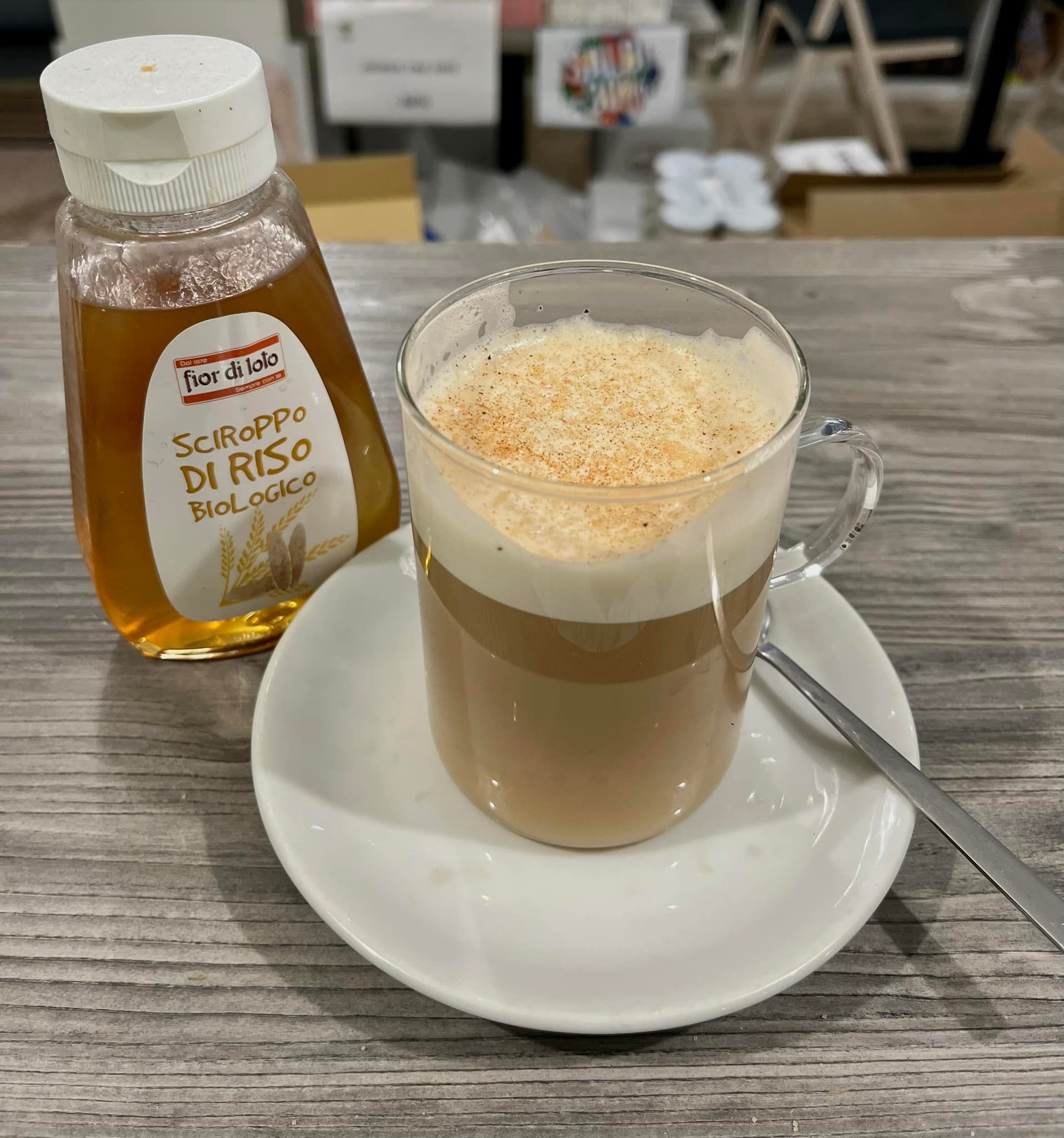Una tazza di caffè su un piattino accanto a una bottiglia di sciroppo di riso