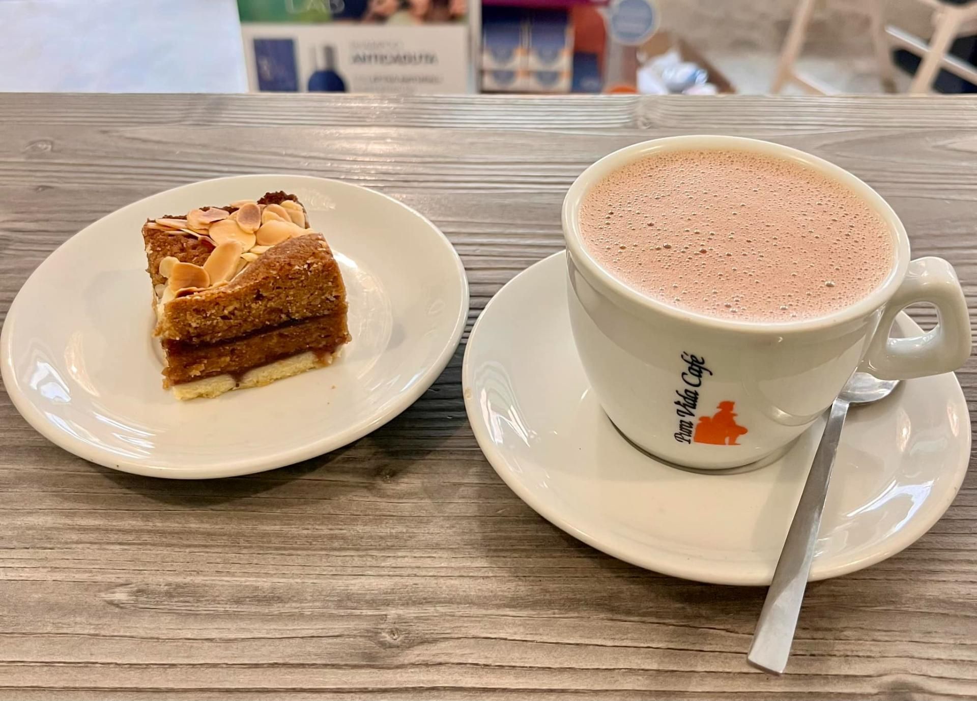 Una tazza di caffè e una fetta di torta su un piattino su un tavolo.