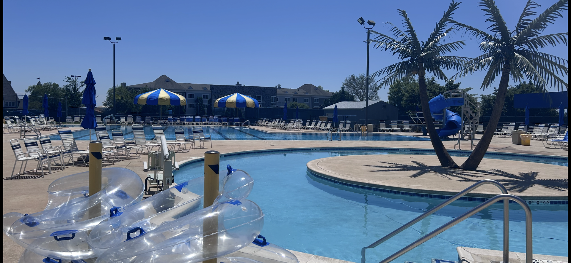 A sunny day at a water park with a lazy river and a pool, palm trees, and clear blue water.