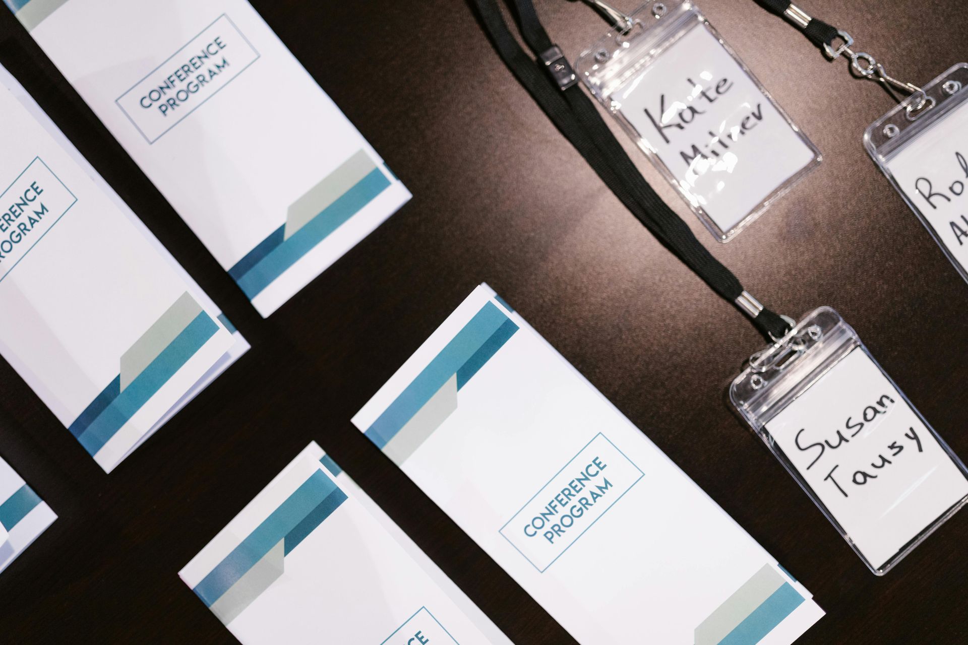 Office supplies and lanyard badges arranged on a dark table with blue-striped packaging.