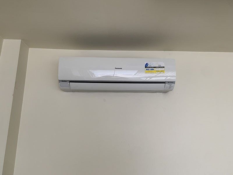 A White Air Conditioner is Hanging on a White Wall — Northside Air Conditioning Services In Aspley, QLD