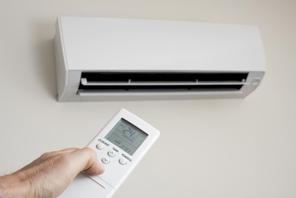 A Person is Holding a Remote Control in Front of an Air Conditioner — Northside Air Conditioning Services In Aspley, QLD