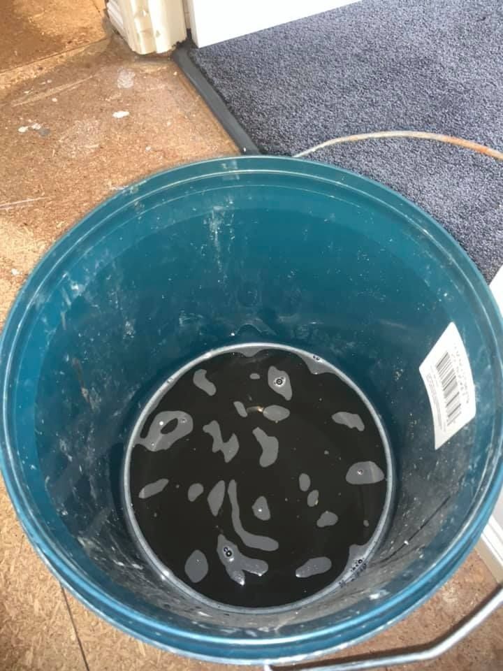 A Blue Bucket Filled With Black Liquid is Sitting on a Floor — Northside Air Conditioning Services In Carseldine, QLD