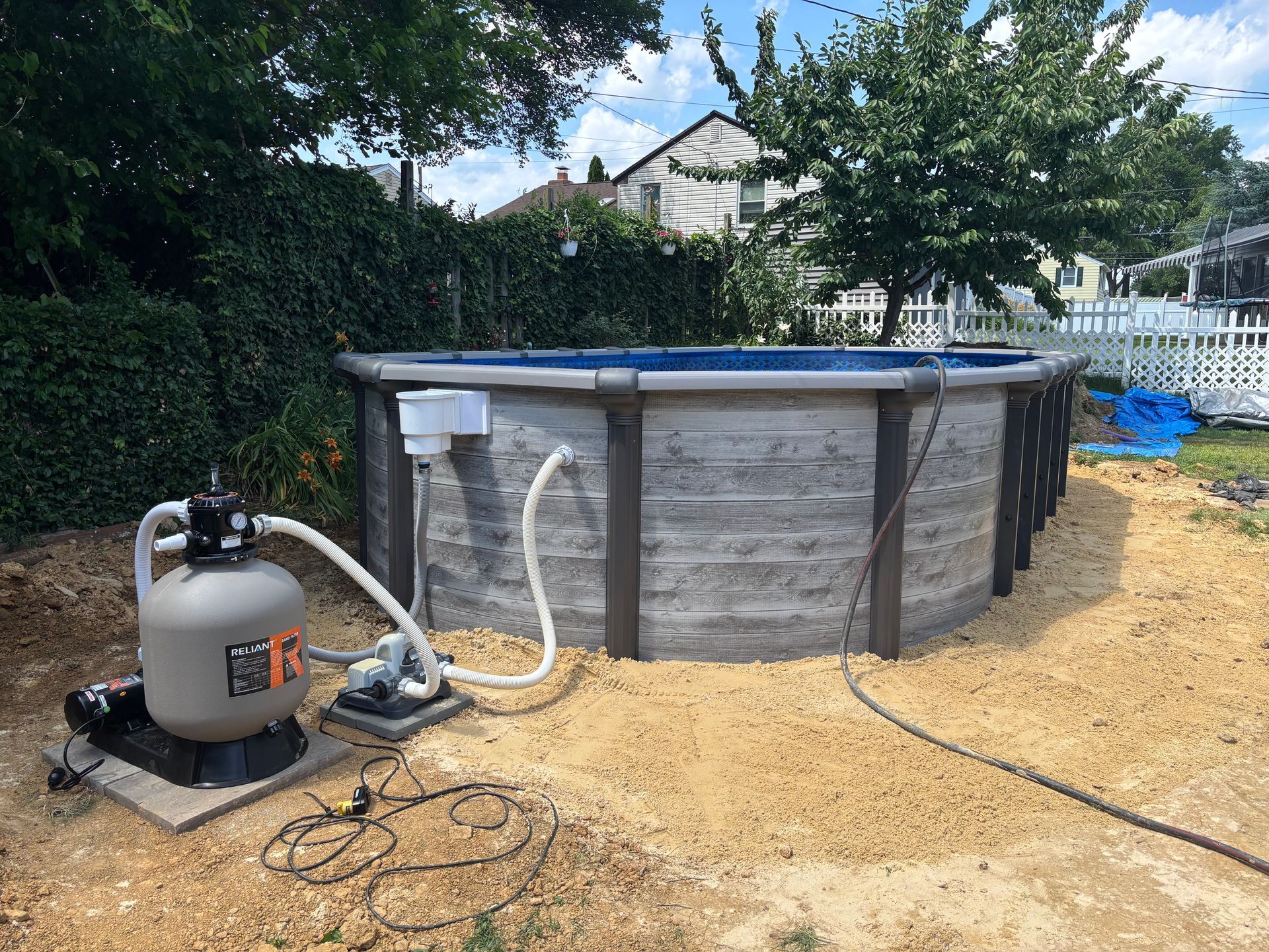A swimming pool is being built in a backyard with a sand filter.