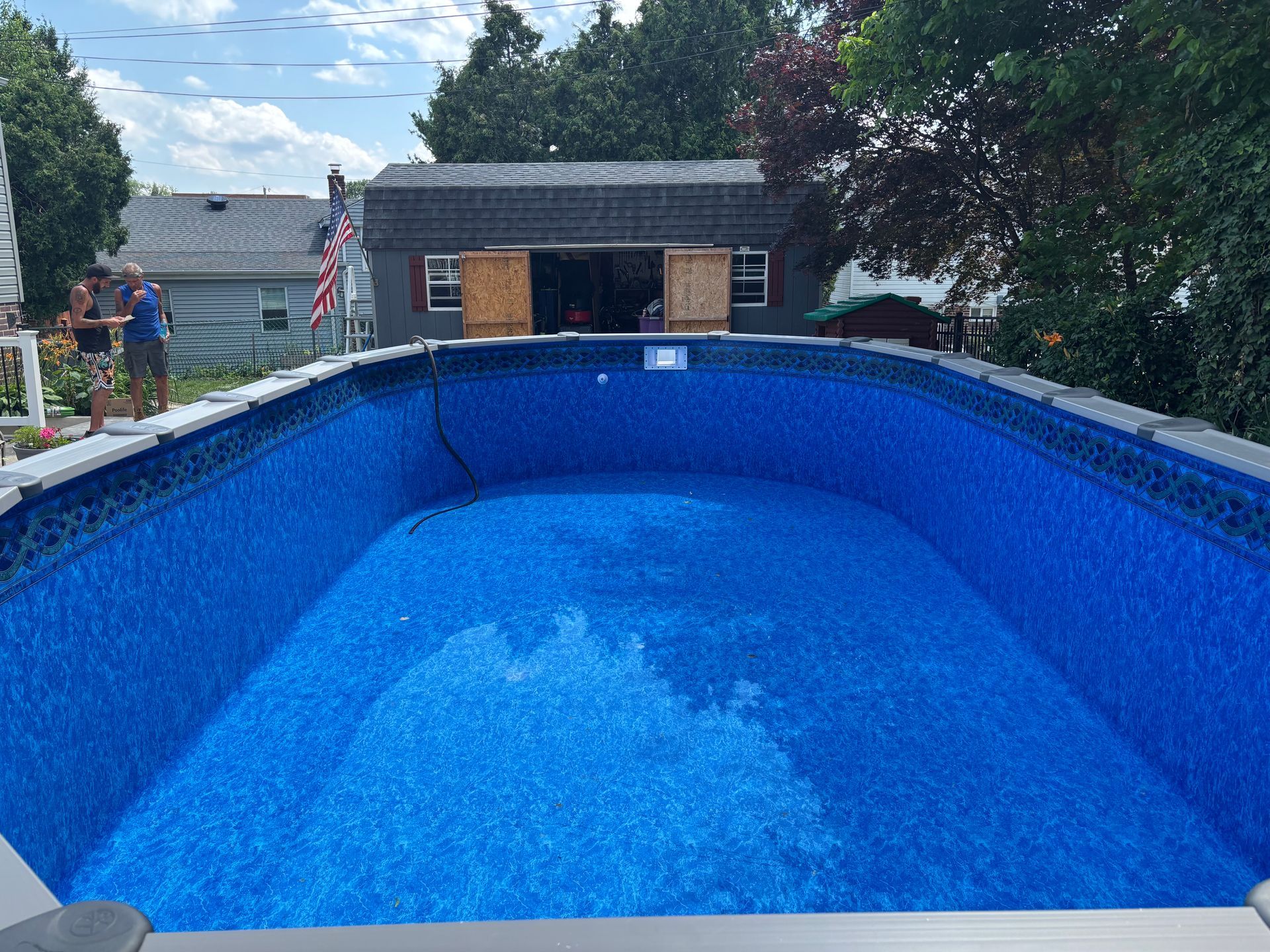 A large blue swimming pool with a shed in the background.