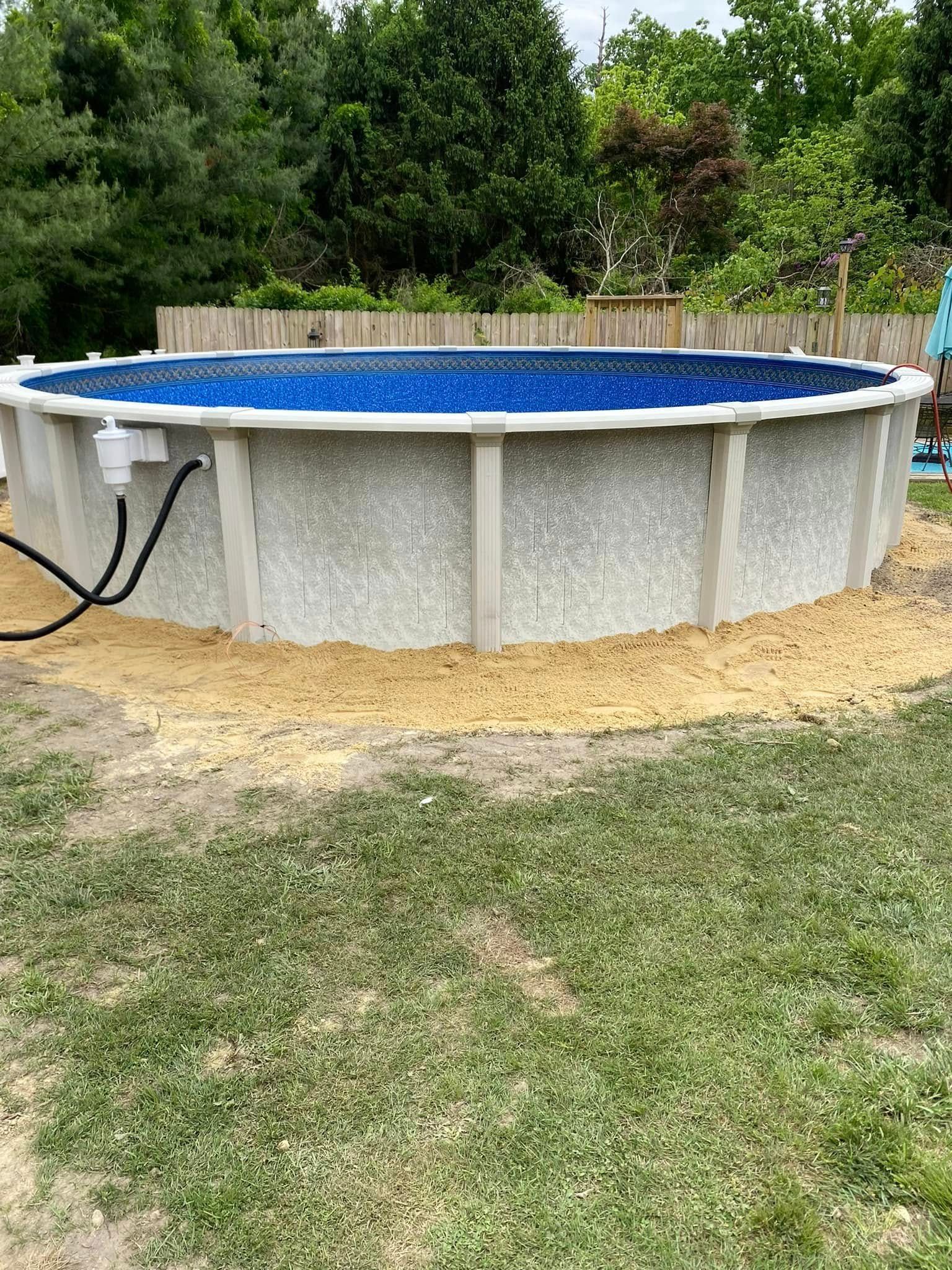 A large swimming pool is sitting in the middle of a lush green field.