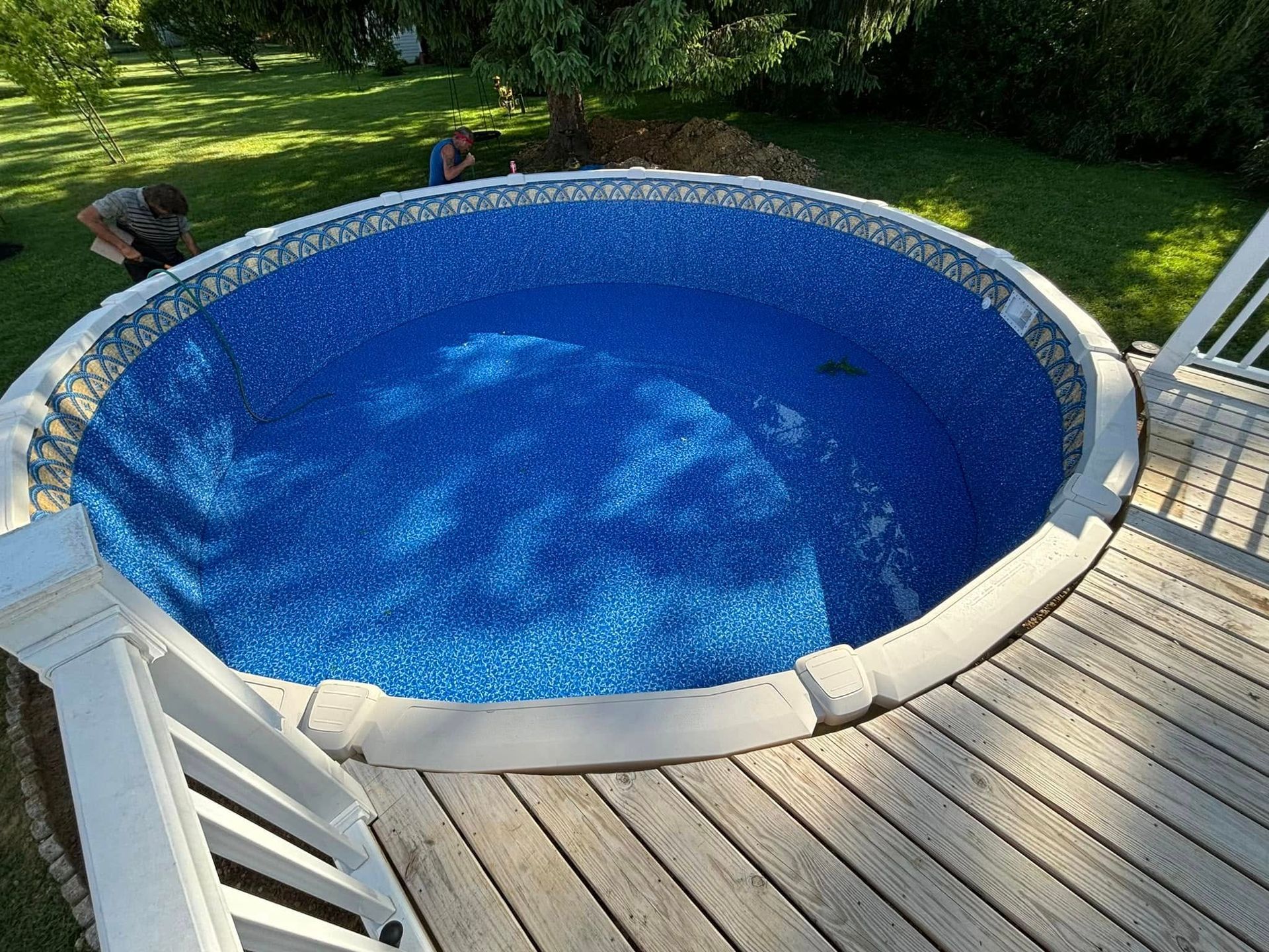 A round pool is sitting on top of a wooden deck.