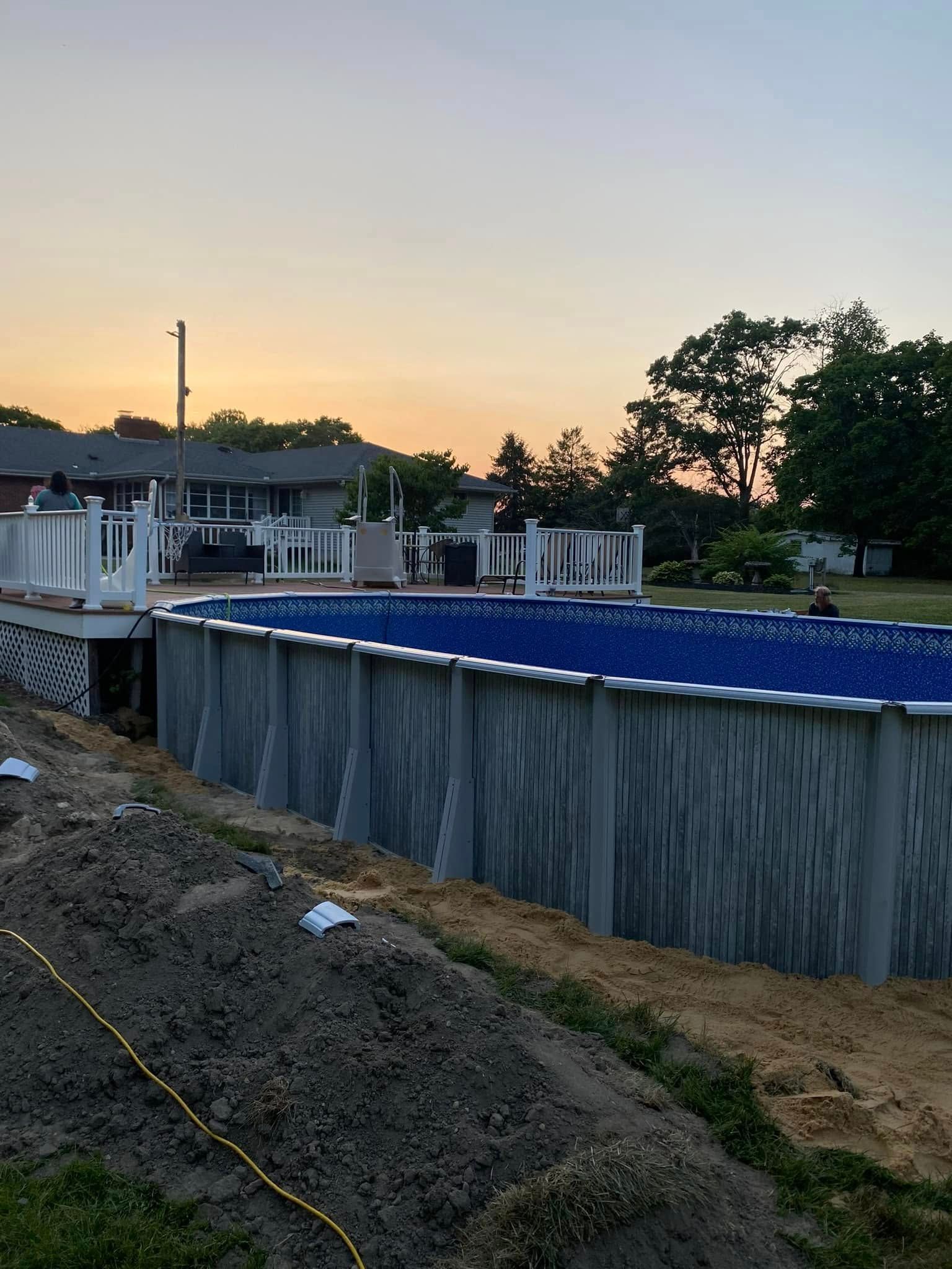 A large swimming pool is being built in the backyard of a house.
