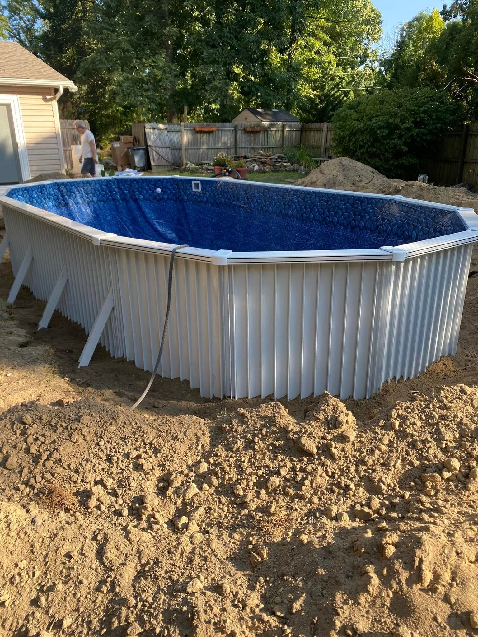 A large white pool is sitting in the middle of a pile of dirt.