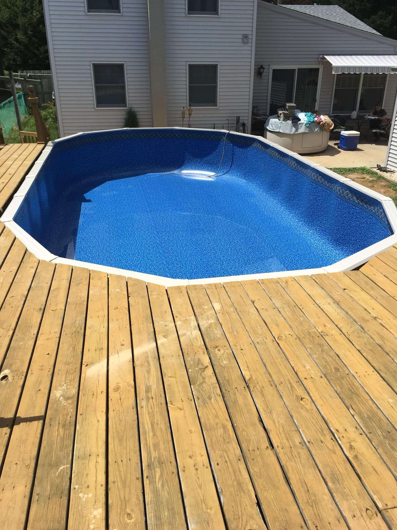 A large swimming pool is sitting on top of a wooden deck.