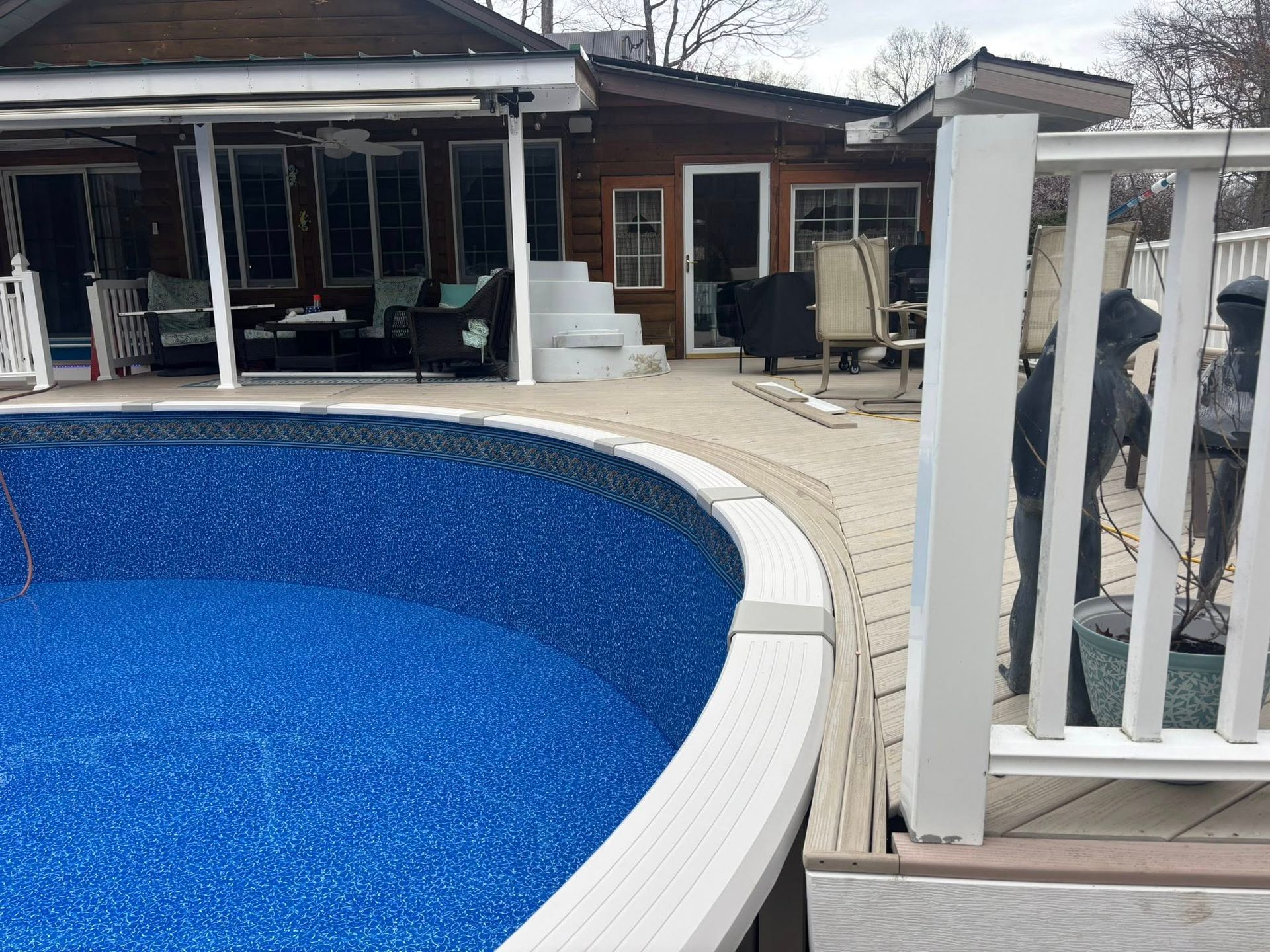 A swimming pool with a white railing and a house in the background