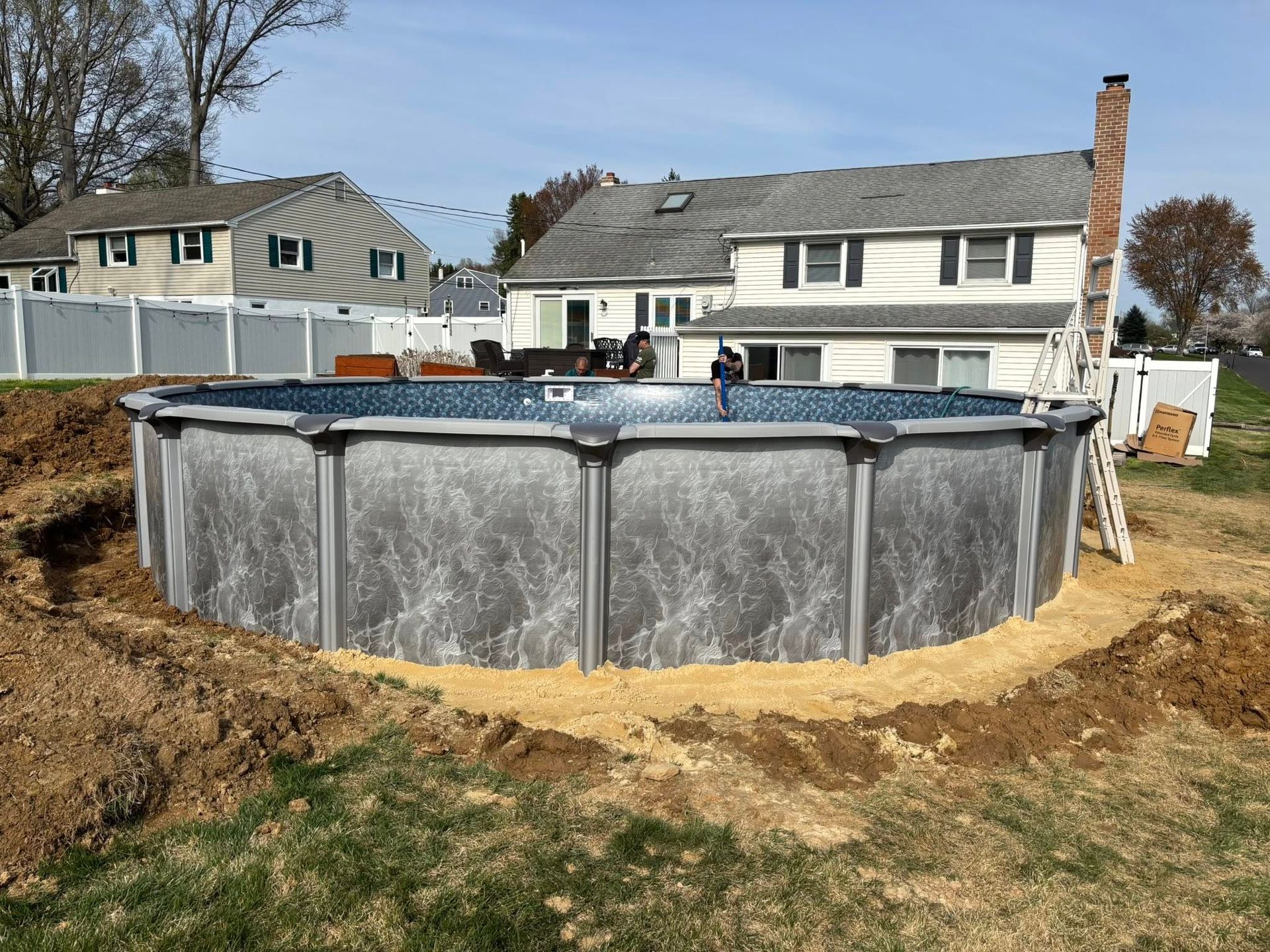 A large swimming pool is being built in the backyard of a house.