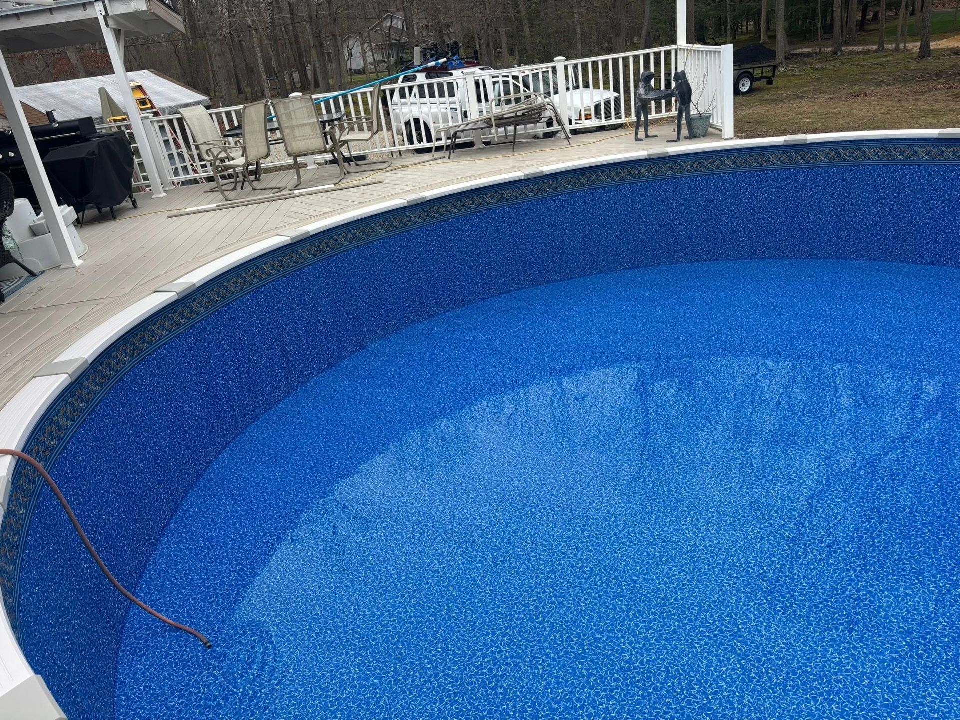A large swimming pool with a deck and chairs around it.