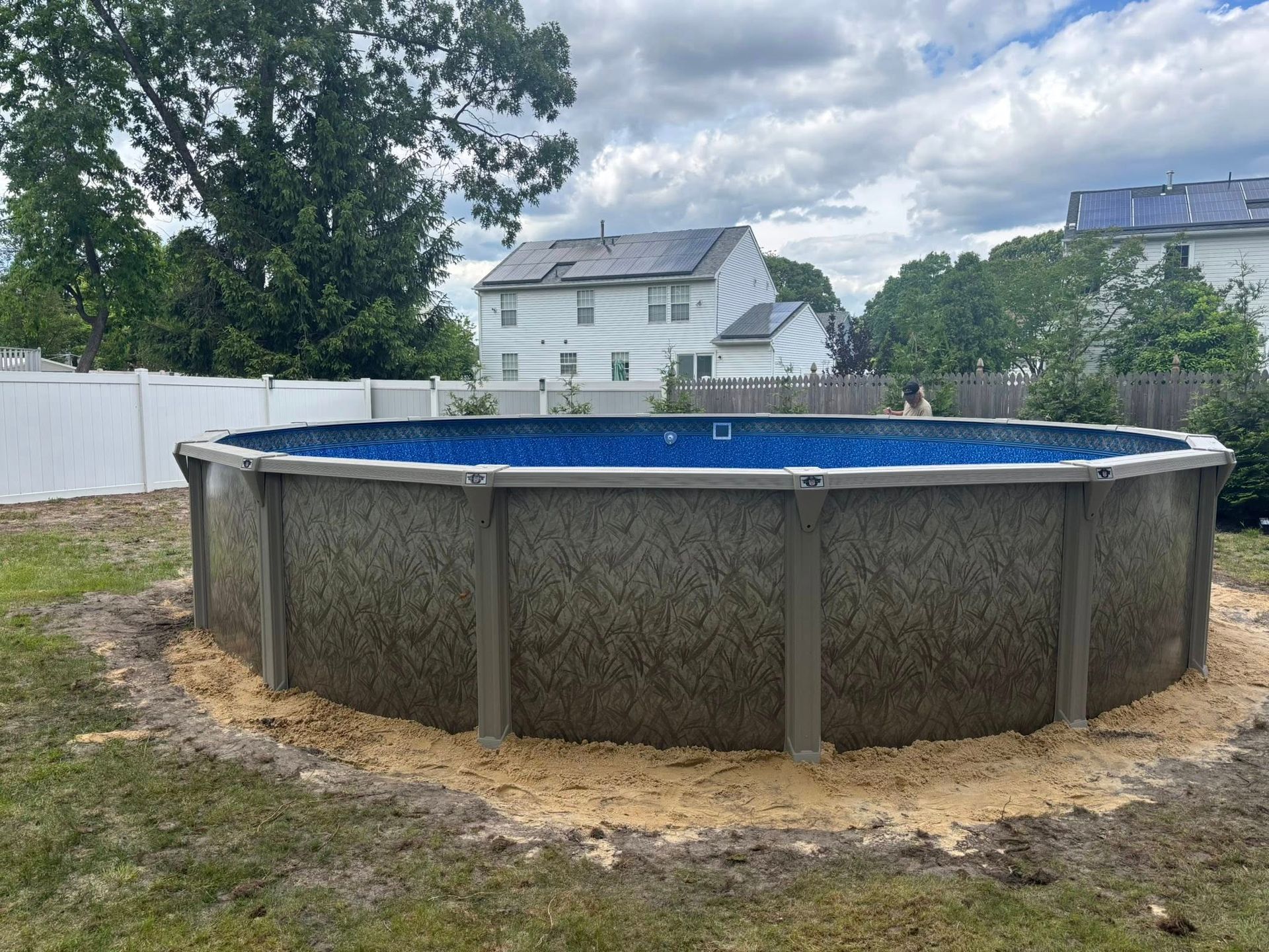 A large swimming pool is sitting in the middle of a backyard.