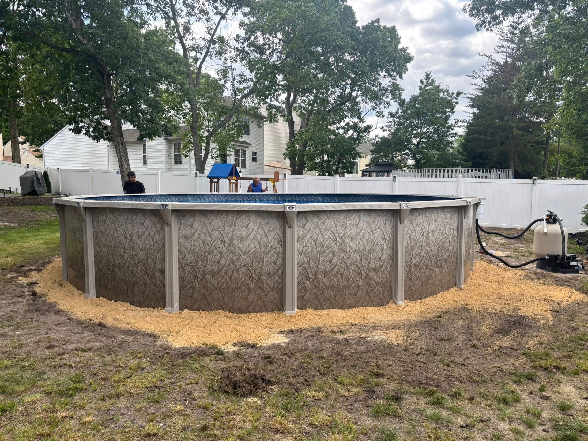 A large swimming pool is sitting in the middle of a yard.