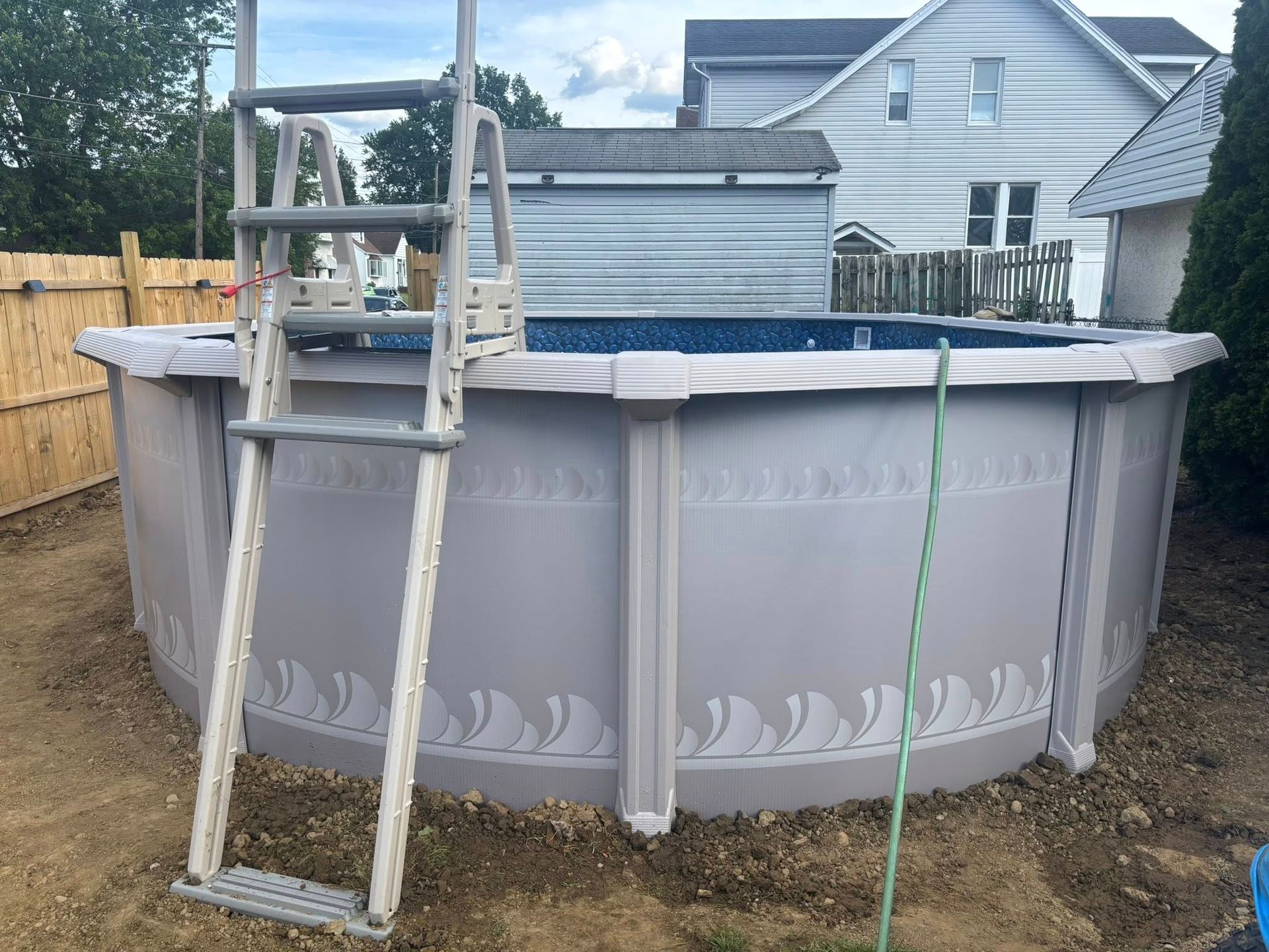 A swimming pool with a ladder attached to it in a backyard.