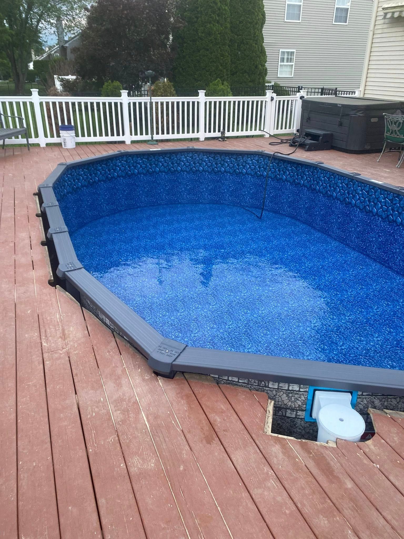 A large swimming pool is sitting on a wooden deck