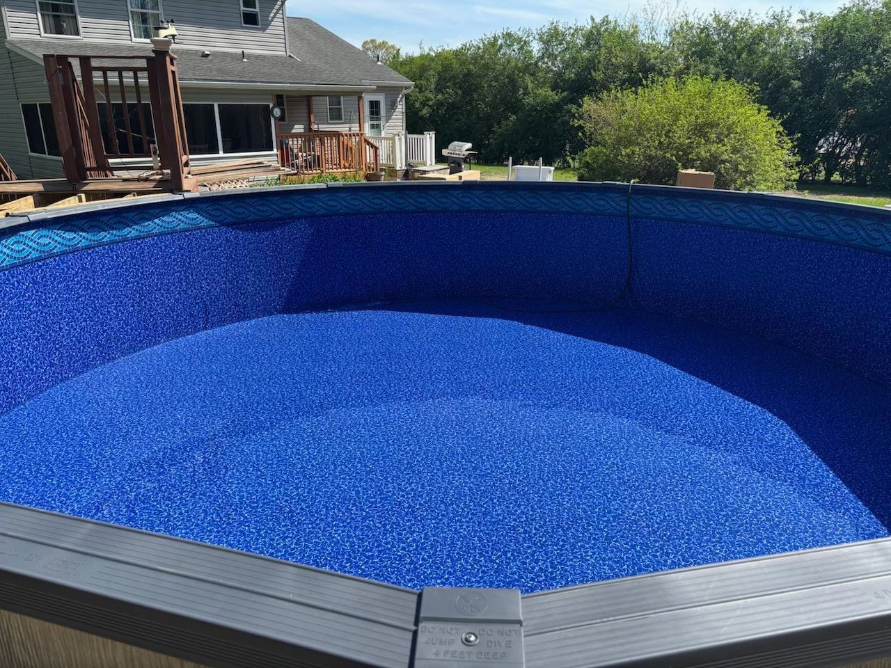 A large swimming pool filled with blue gravel in front of a house.