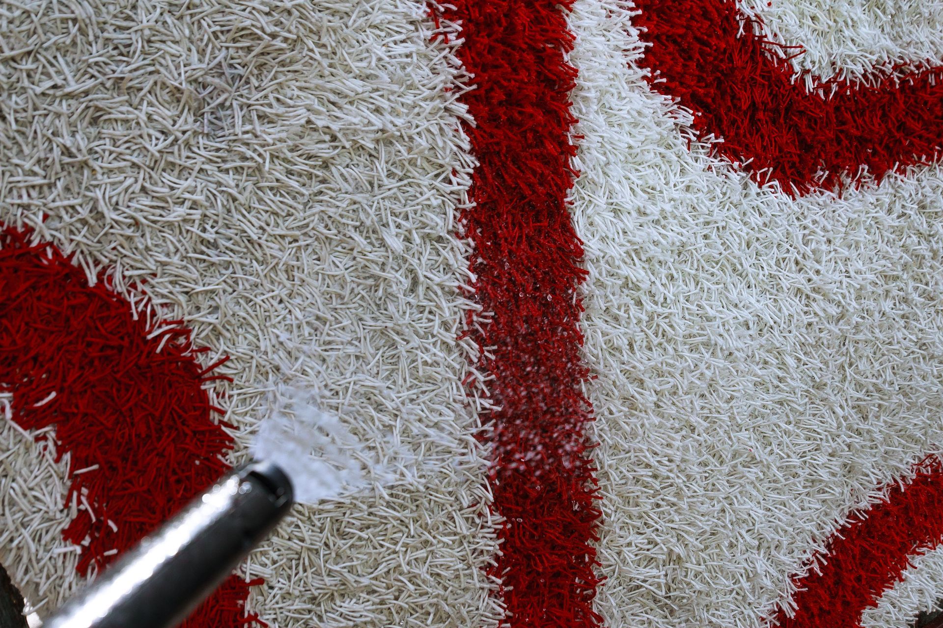 Primo piano di un tappeto a fantasia bianca e rossa mentre viene pulito con un aspirapolvere.