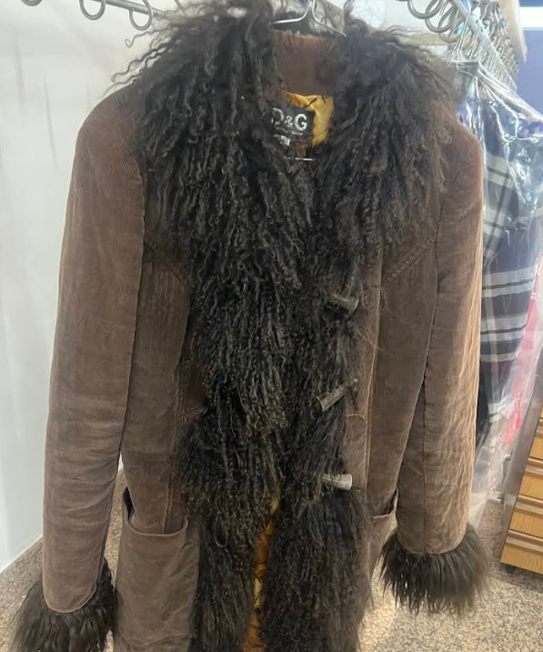 Cappotto in pelle scamosciata marrone con finiture in pelliccia scura e chiusure a strappo.