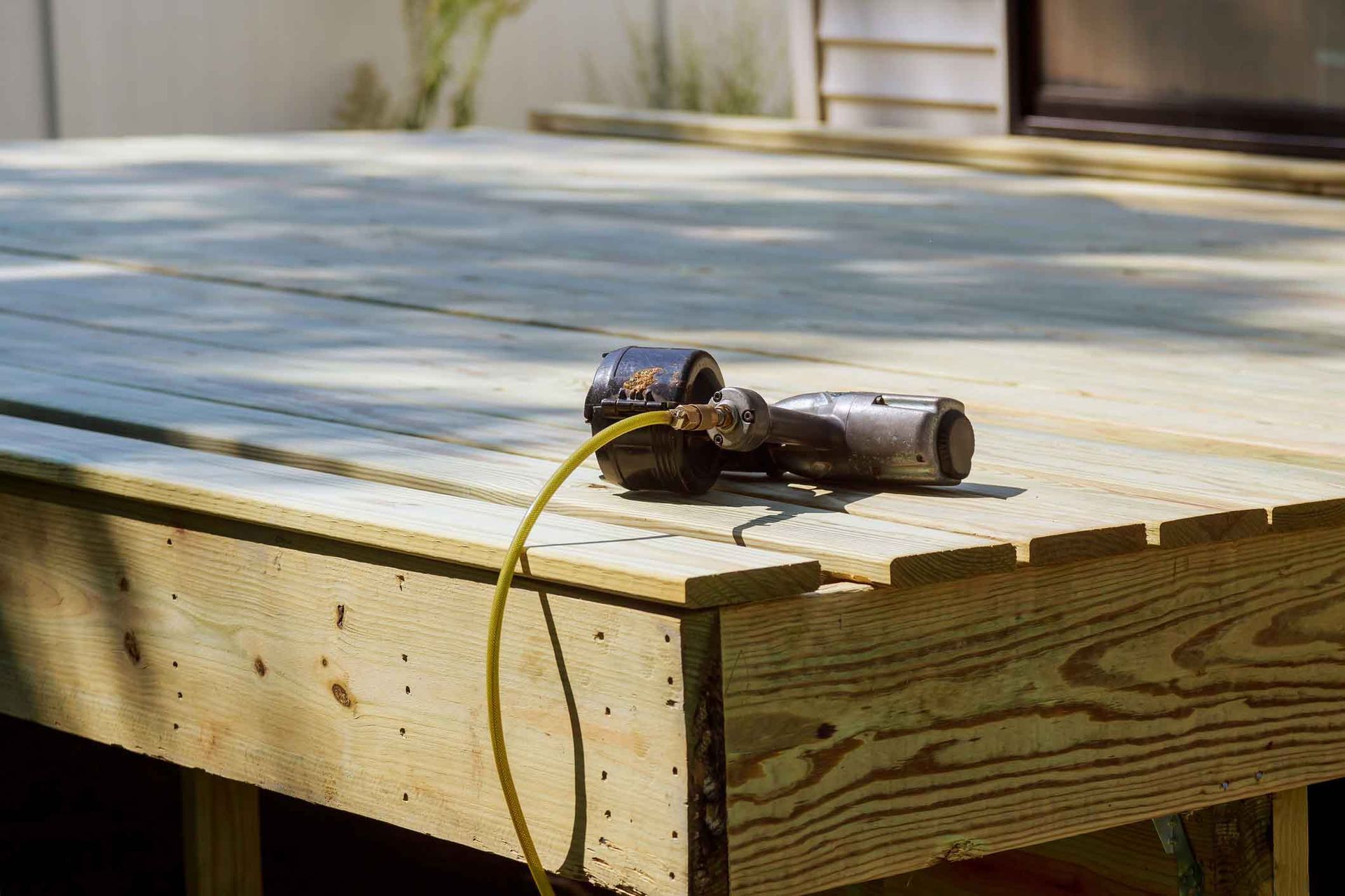 A drill is sitting on top of a wooden deck.
