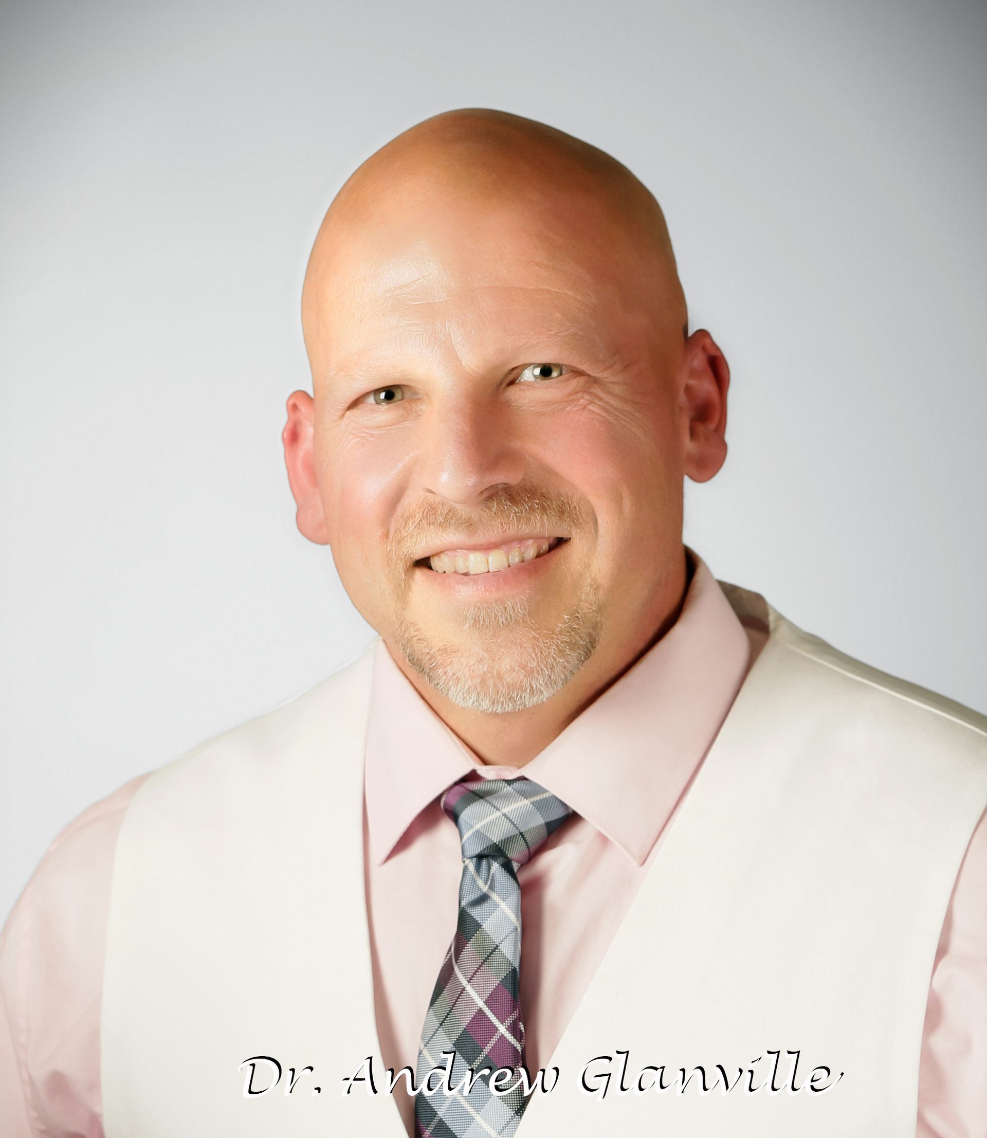 A bald man in a pink shirt and tie is smiling