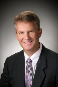 A man in a suit and tie is smiling for the camera.