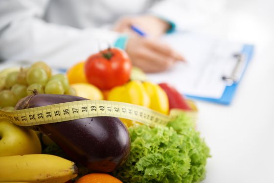 A person is measuring fruits and vegetables with a tape measure.