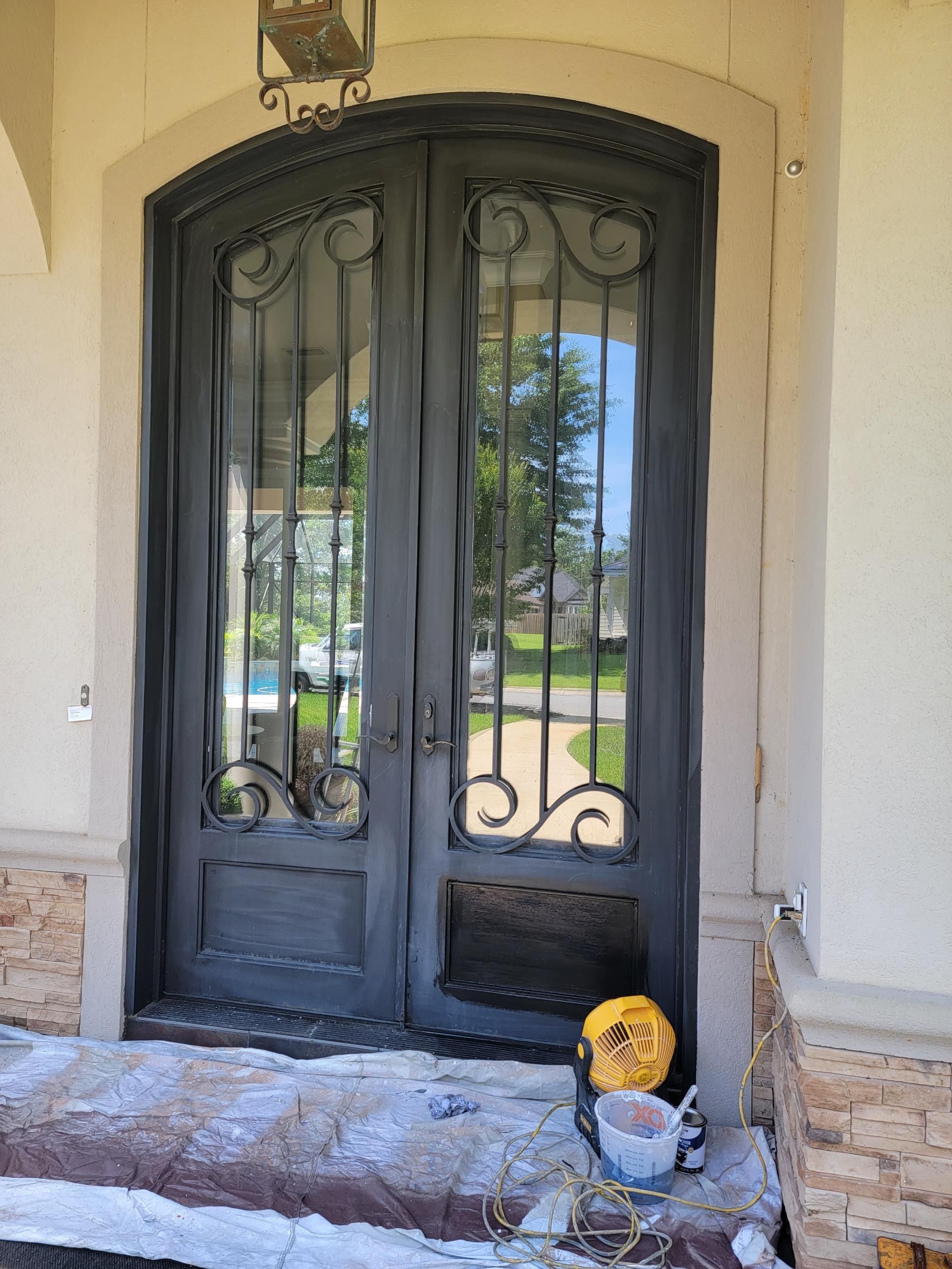 Double dark gray iron doors with glass panes, ornate detailing, and a decorative light fixture above.