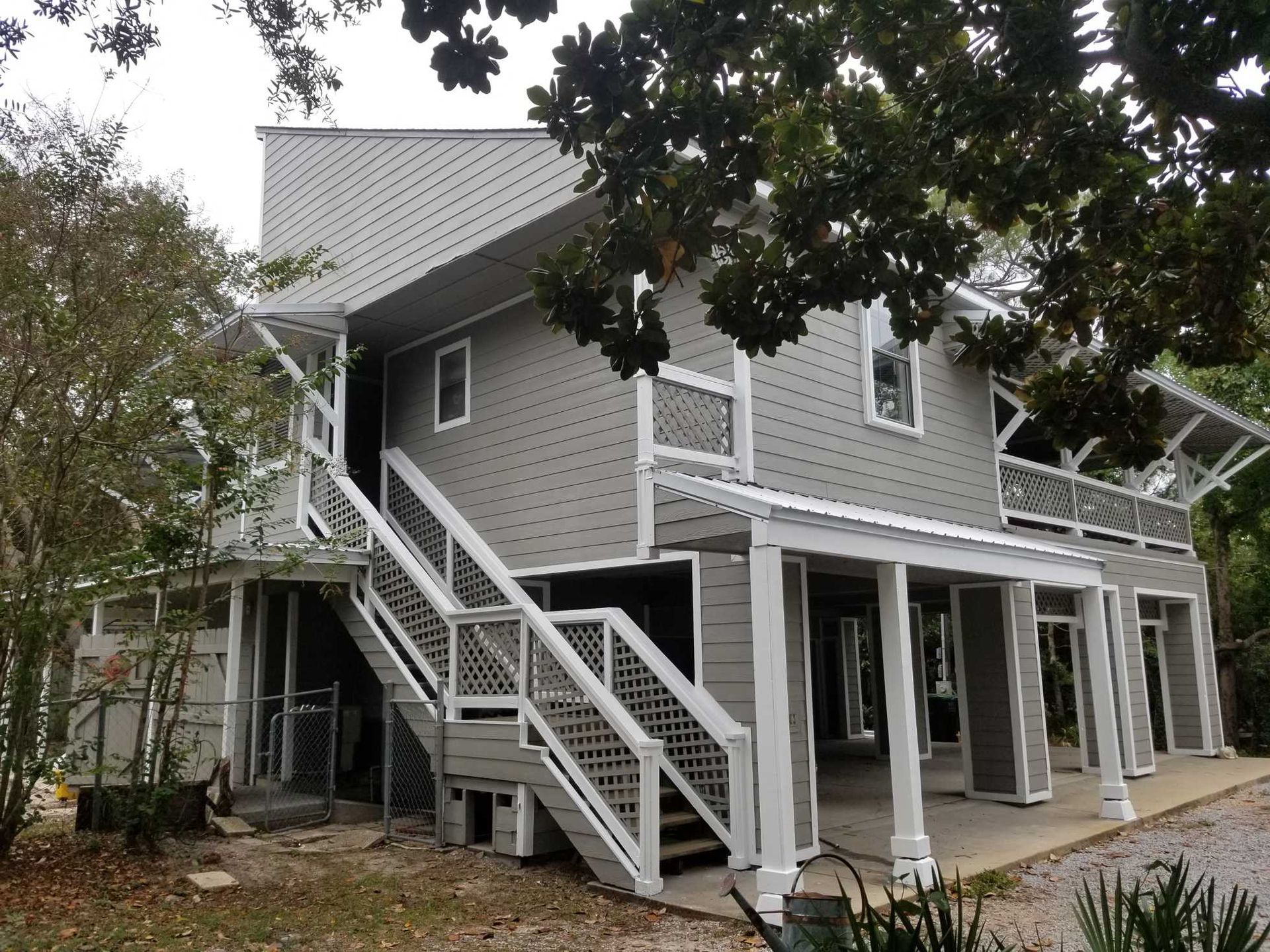 Screened porch overlooking water, furnished with chairs. Blue ceiling, wooden floor.