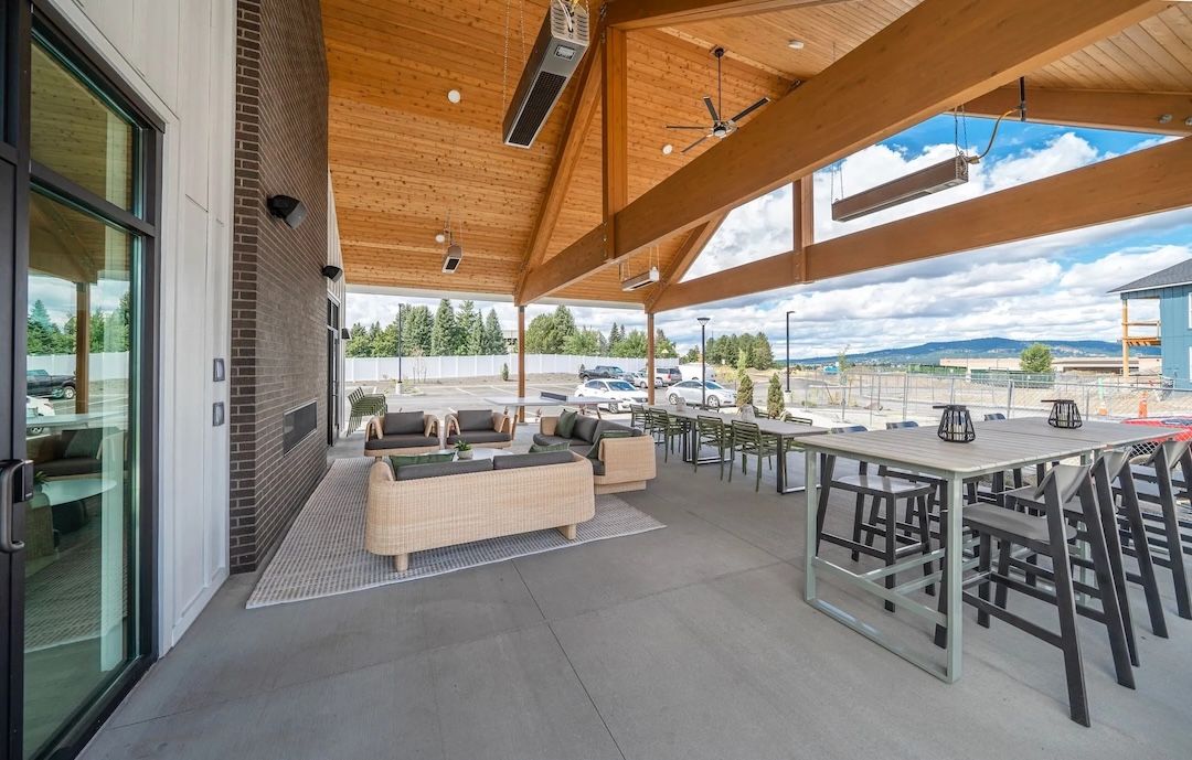 A large covered outdoor patio featuring a vaulted wooden ceiling sheltering lounge seating and dining tables.