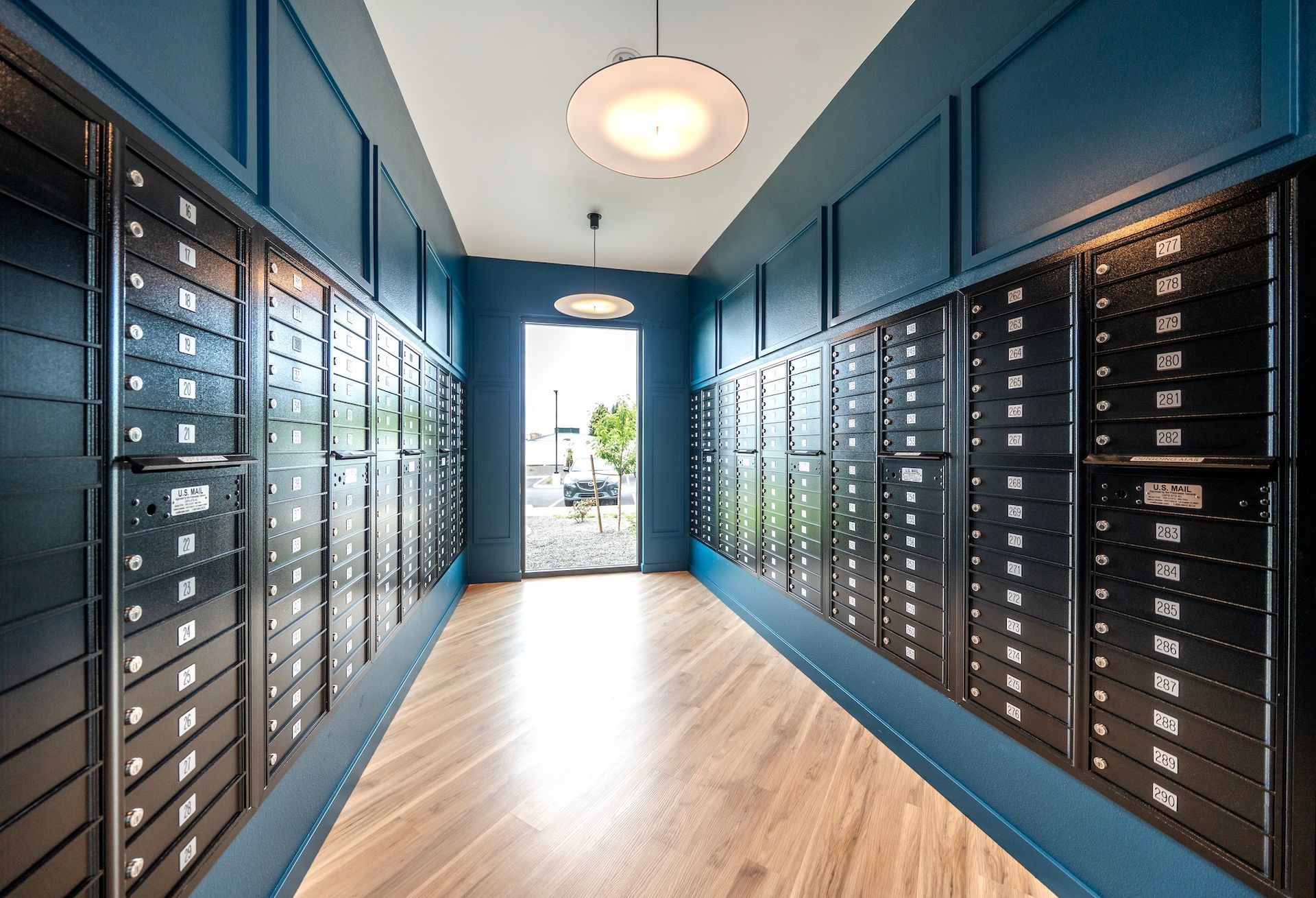 Hallway with rows of black mailboxes, blue walls, and a wooden floor.