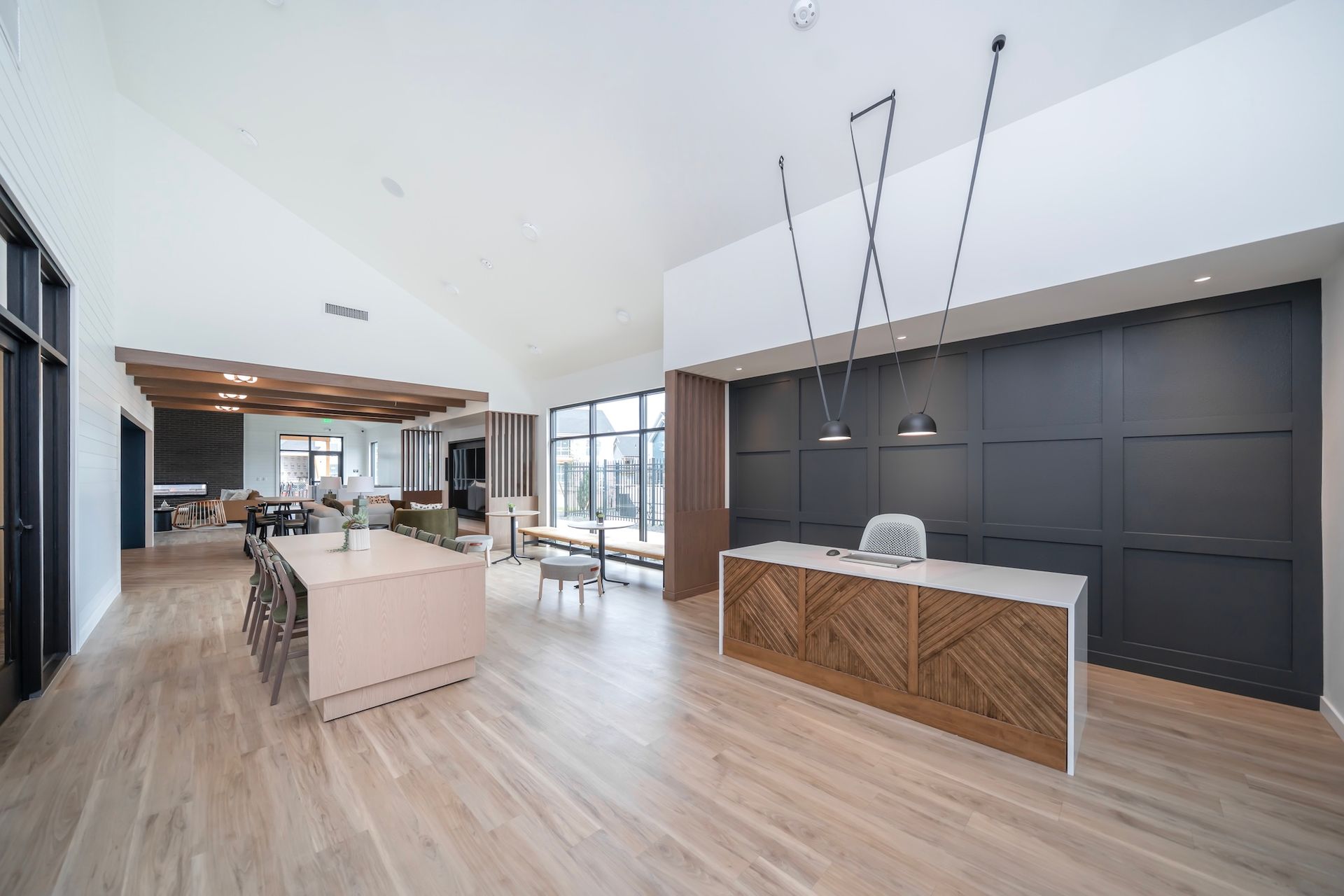 Modern open-plan reception area with light wood floors, a kitchen island, and a textured wooden reception desk.