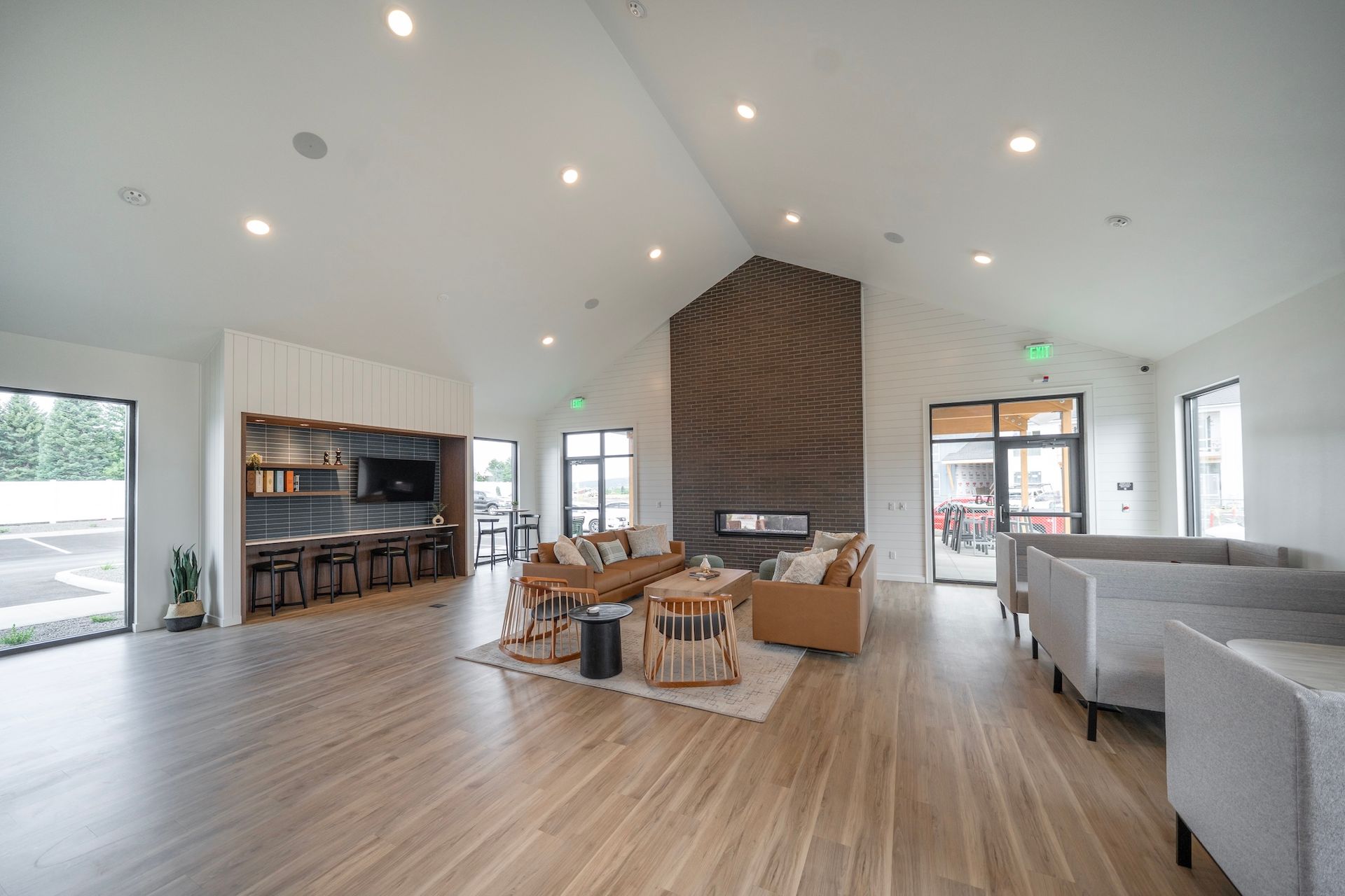 Spacious, modern lounge with fireplace, seating, and large windows, likely in a community center or apartment building.