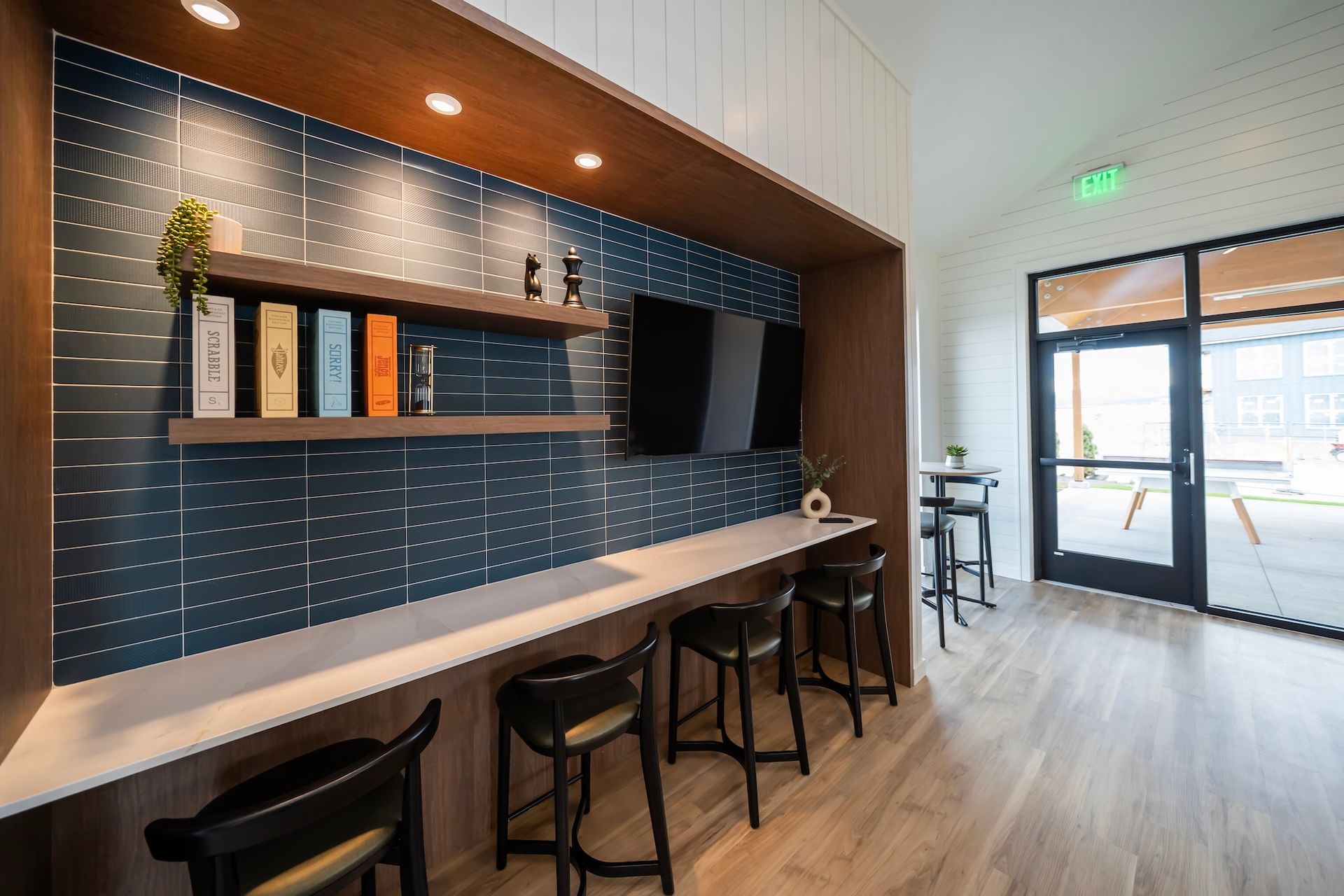 Cozy lounge area with a counter, stools, TV, books, and door to an outdoor patio.