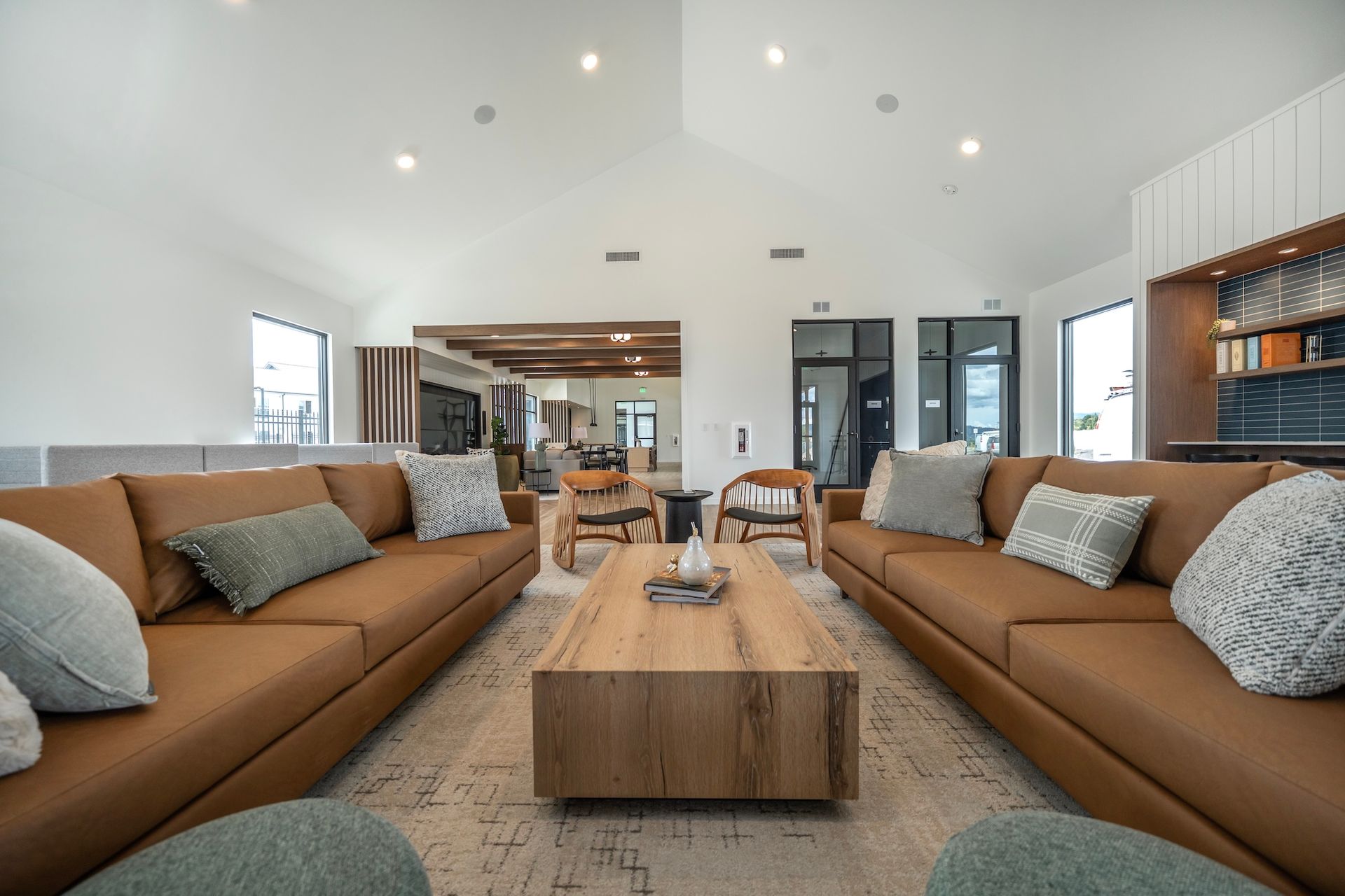 Spacious living room with brown leather sofas, a wooden coffee table, and large windows.
