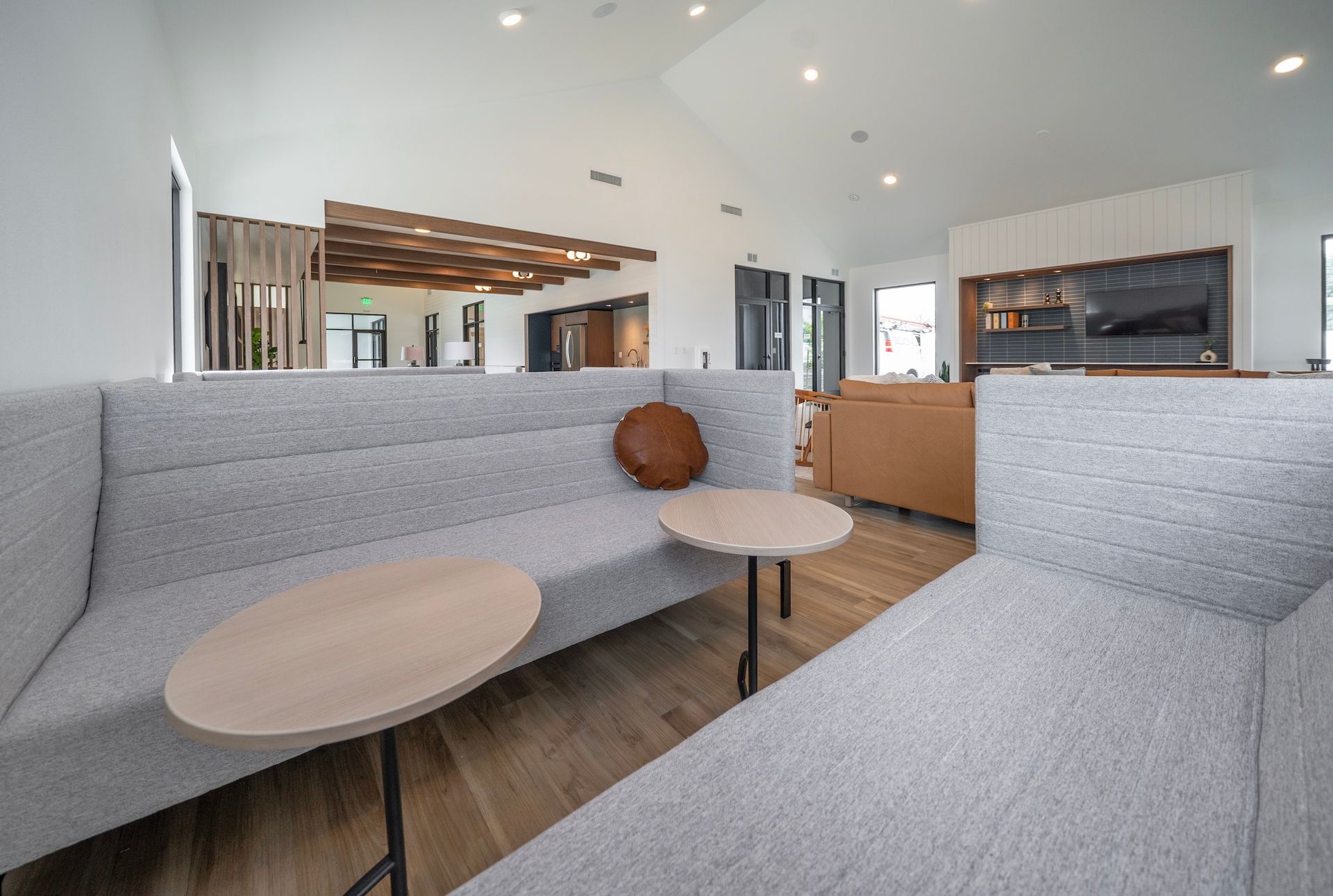 Modern lounge with gray sectional sofa, wooden tables, and neutral decor.