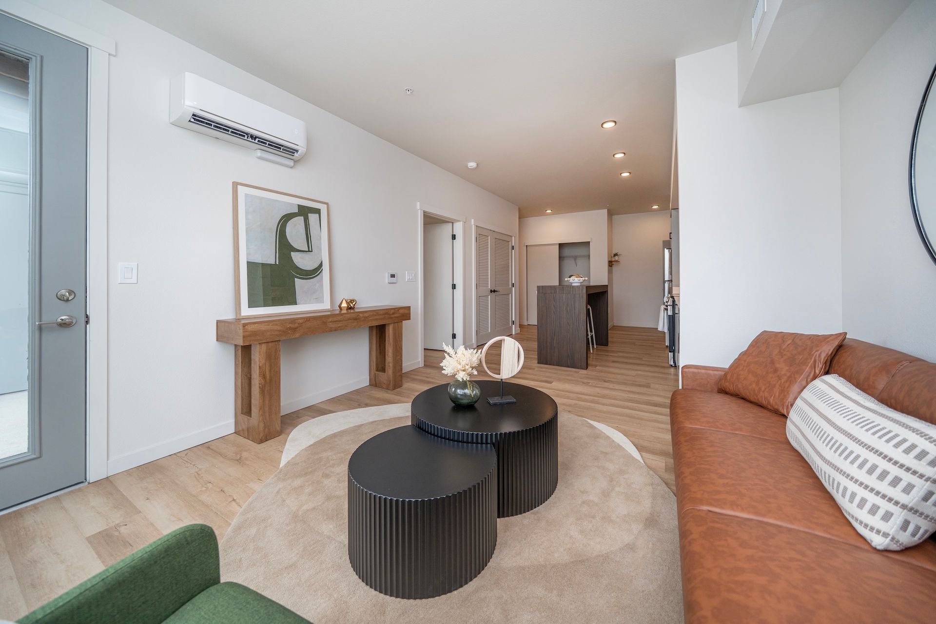 Modern living room with leather couch, coffee tables, and art.