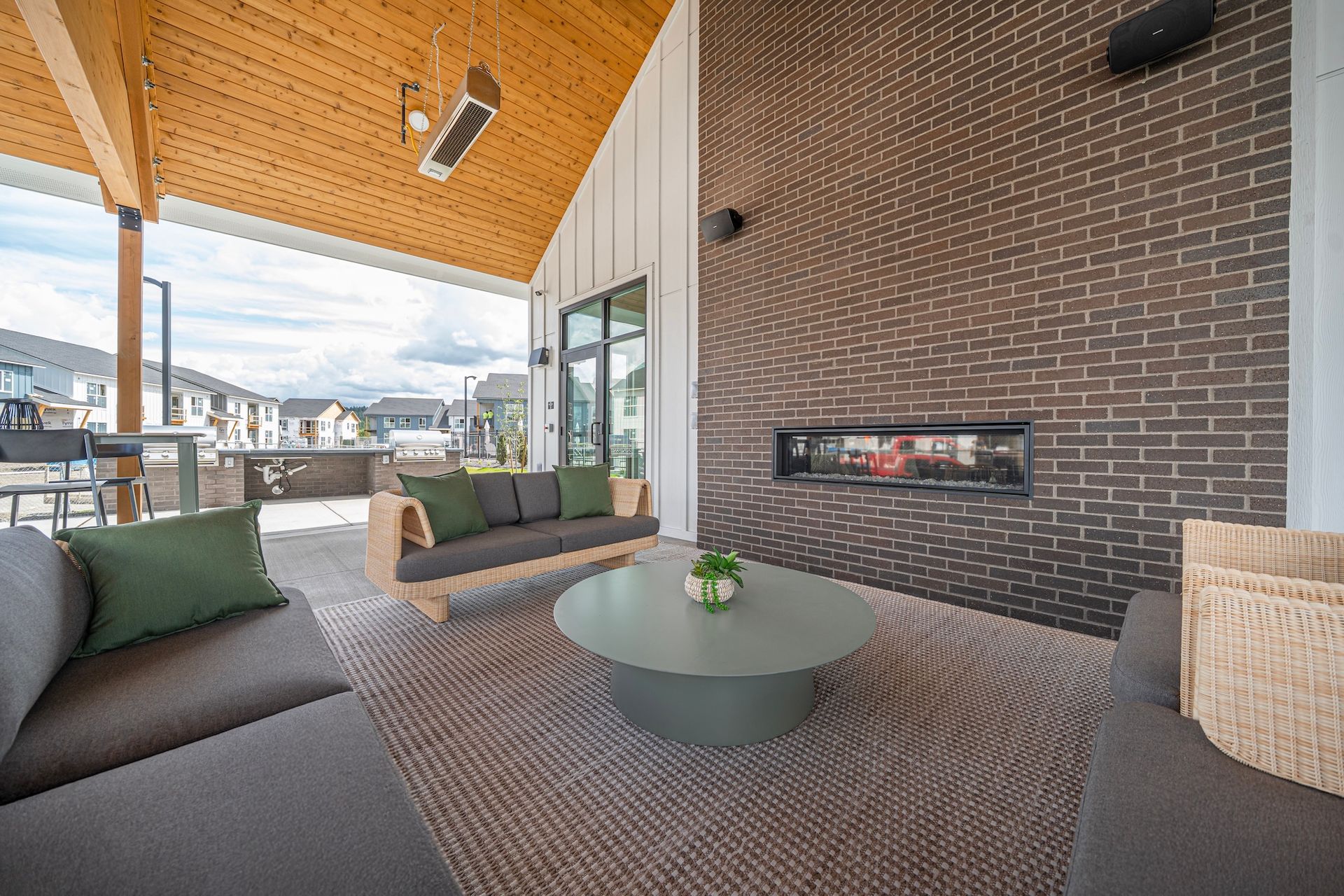 Outdoor patio with seating, a fireplace, and a view of residential buildings.