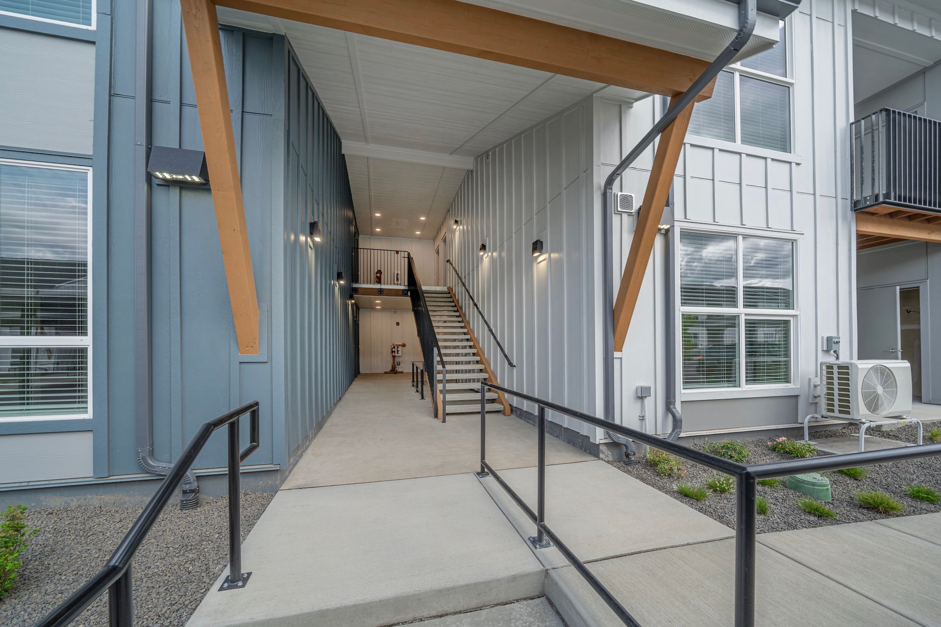 Exterior entrance with ramp, stairs, metal siding, and wooden beams.