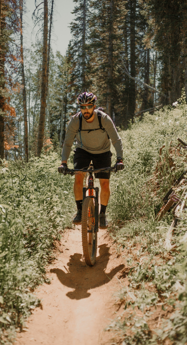 A man is riding a mountain bike on a trail in the woods.